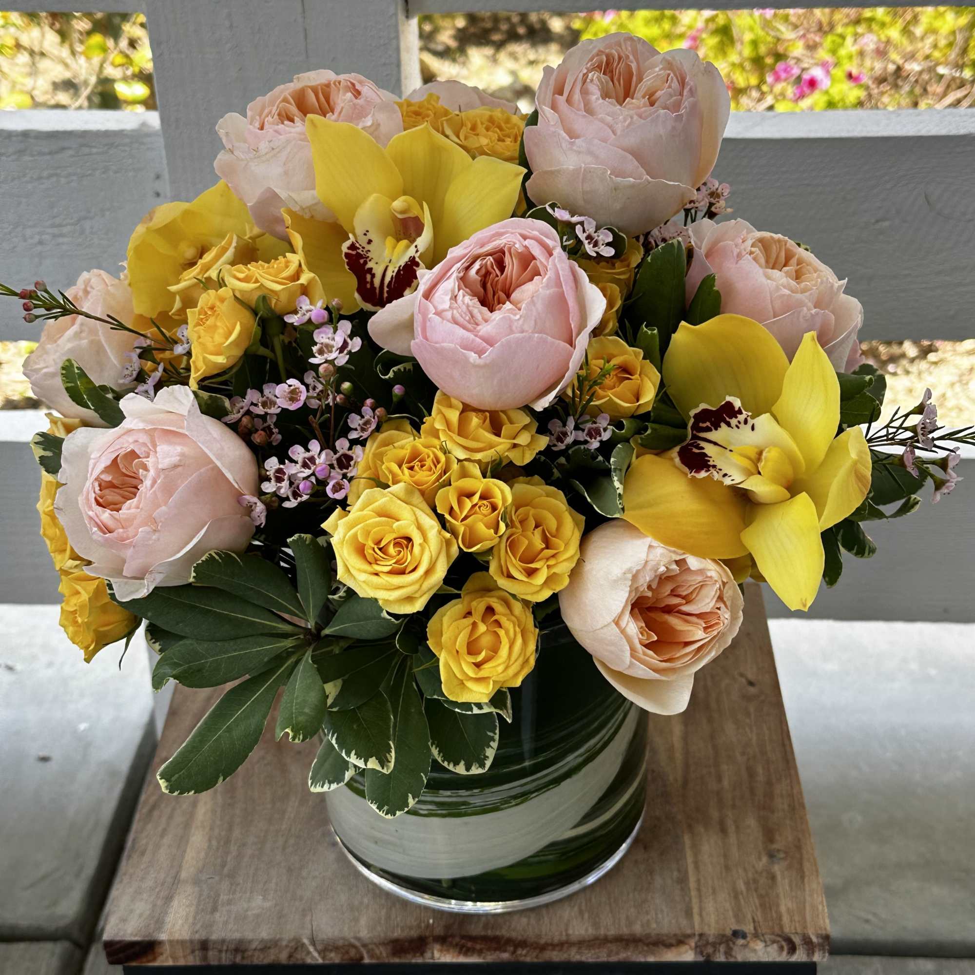 Garden roses, spray roses, orchids, wax flower and  seasonal greenery.