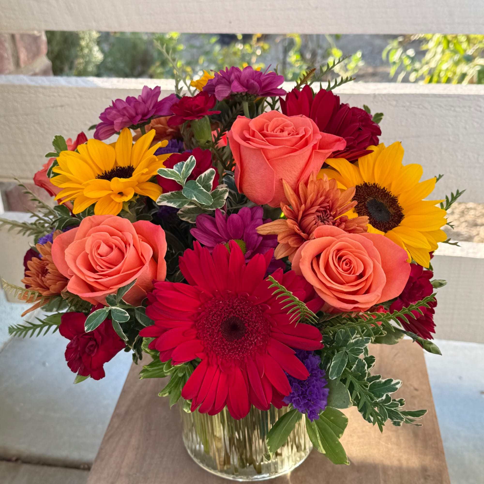 Mixed bouquet of roses, gerbera daisies, and chrysanthemums in a glass vase