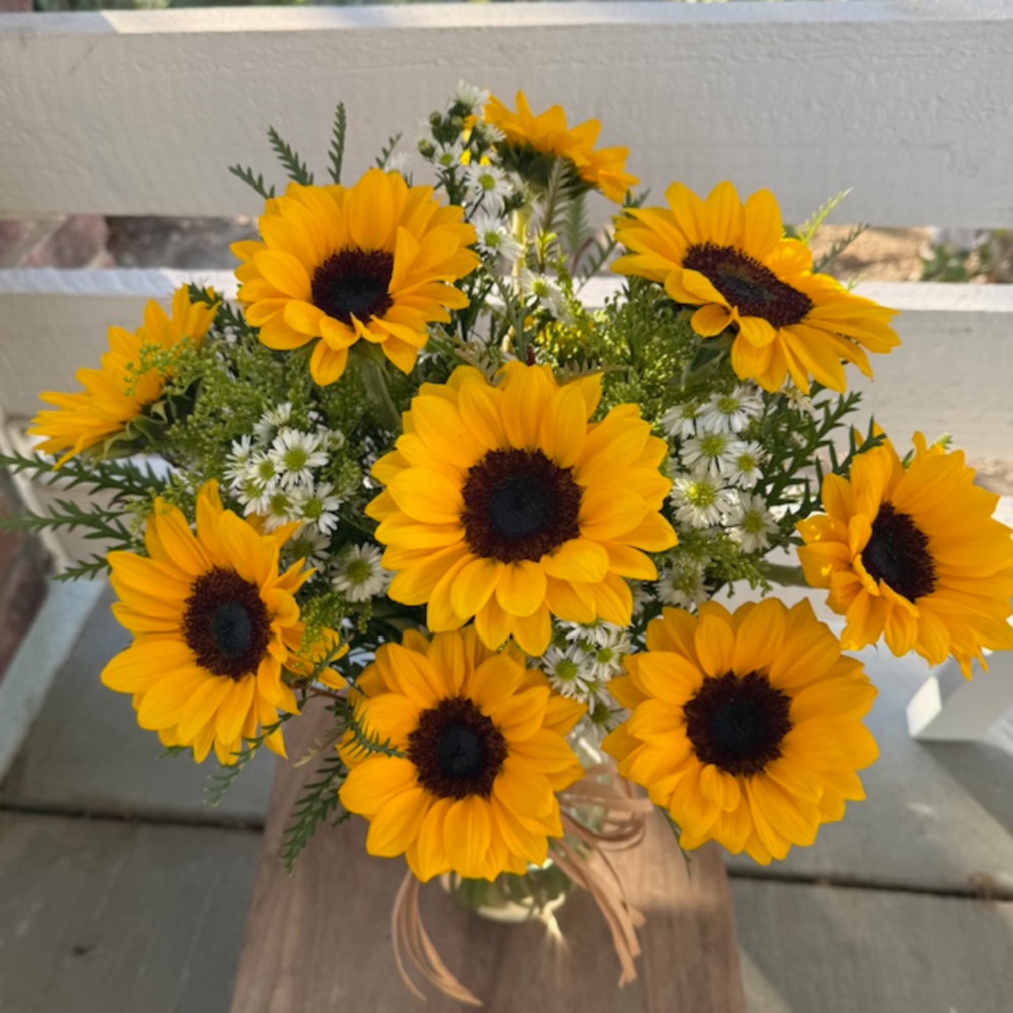 Bouquet of yellow sunflowers and small white daisies in a glass vase