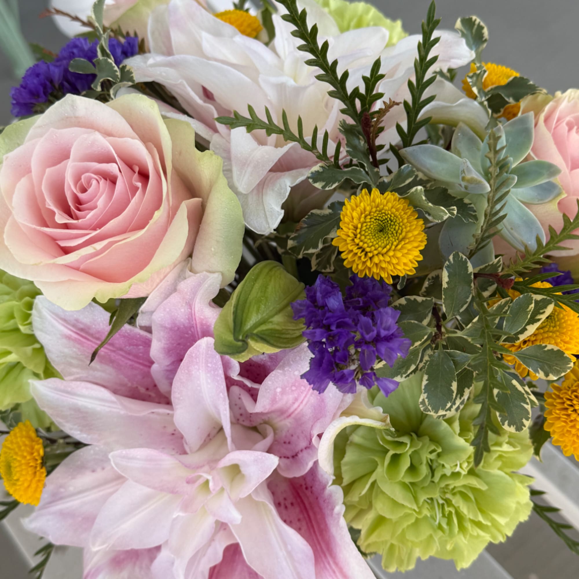 Bouquet of pink roses, white lilies, and green carnations with yellow button mums