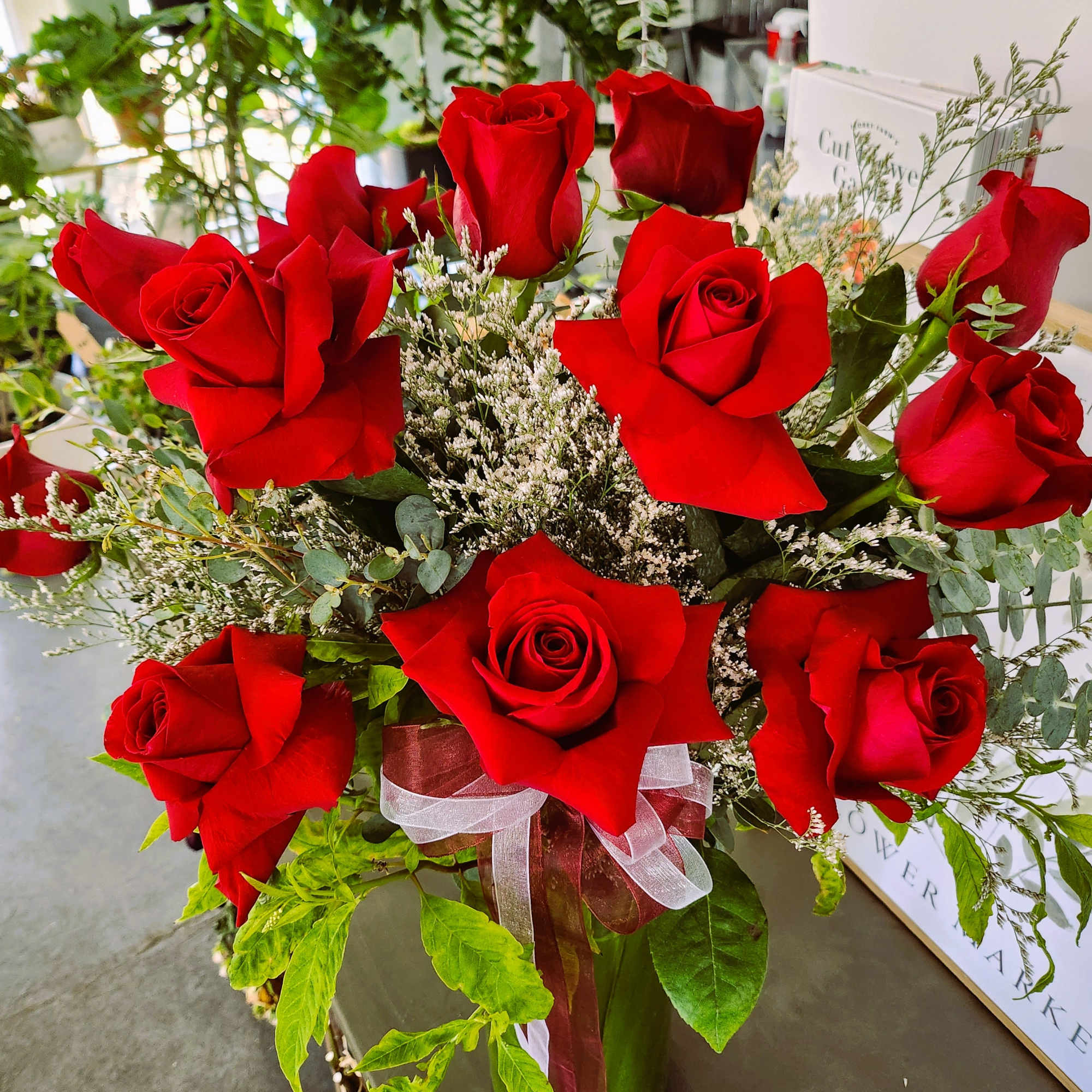 Bouquet of red roses with white filler flowers in a wrapped vase