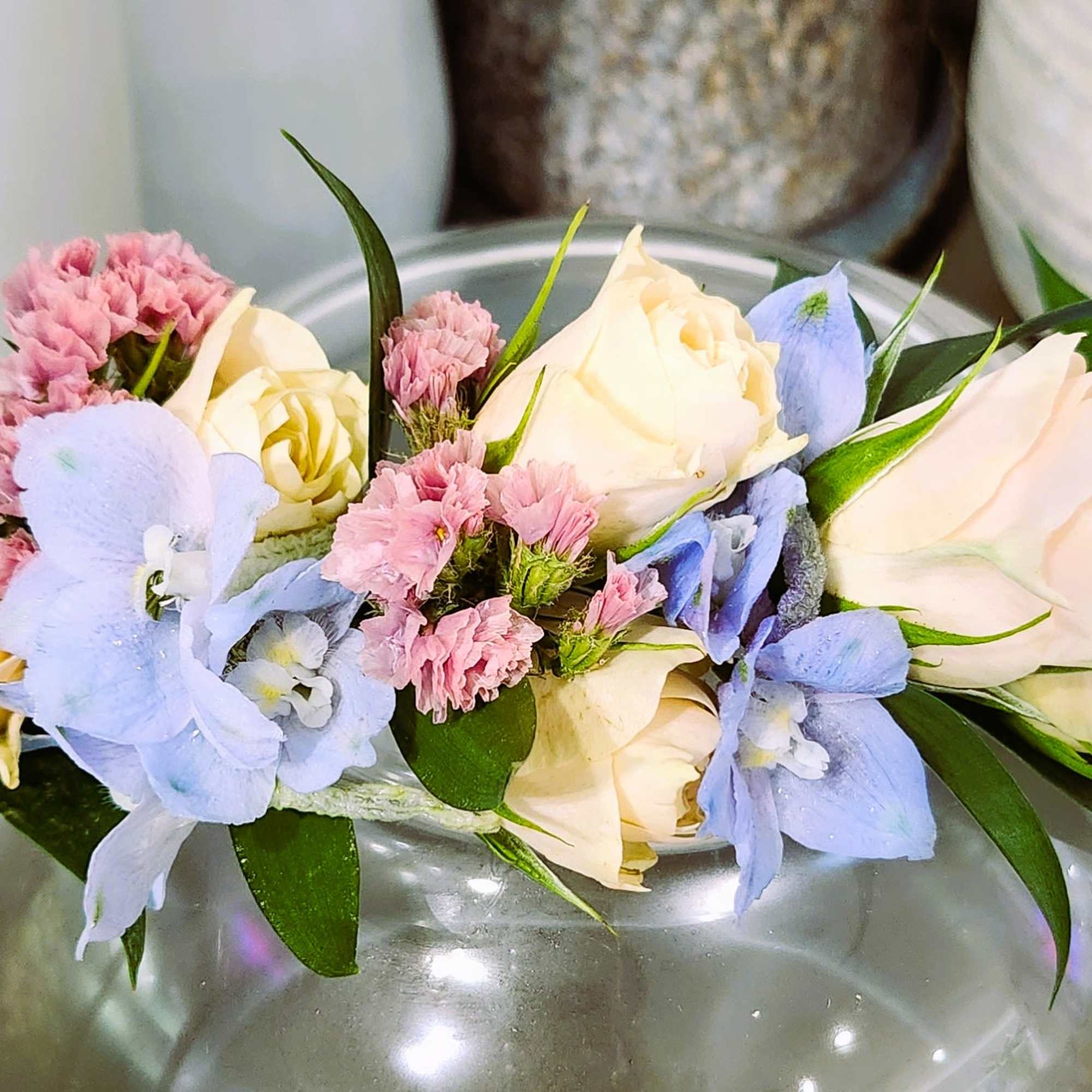 Pastel flower arrangement with roses and blue blossoms in a glass vase