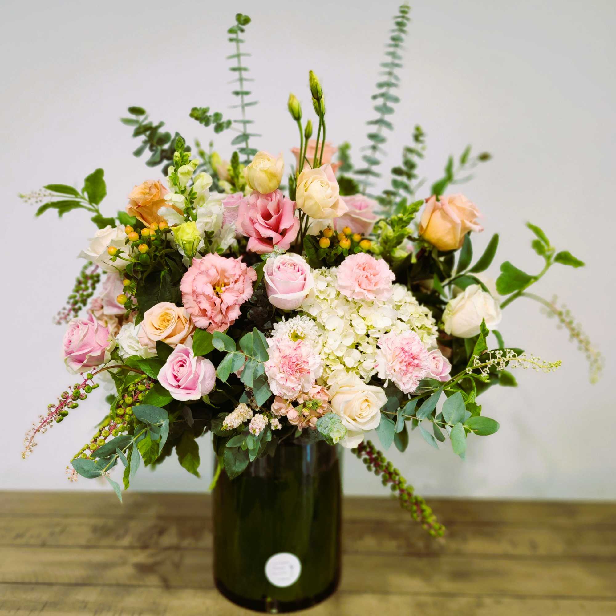 Pink and cream mixed bouquet in a dark glass vase