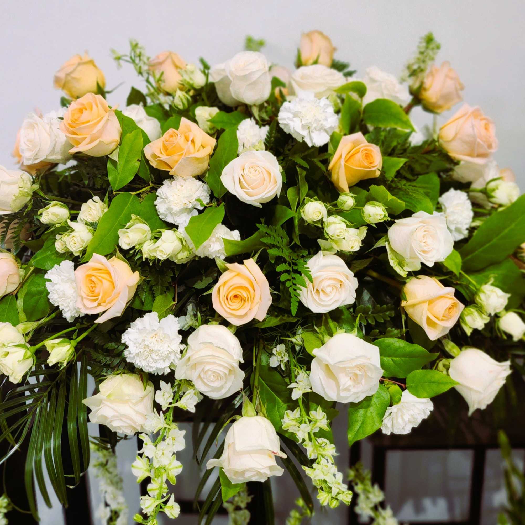 Large arrangement of pale peach and white roses with greenery
