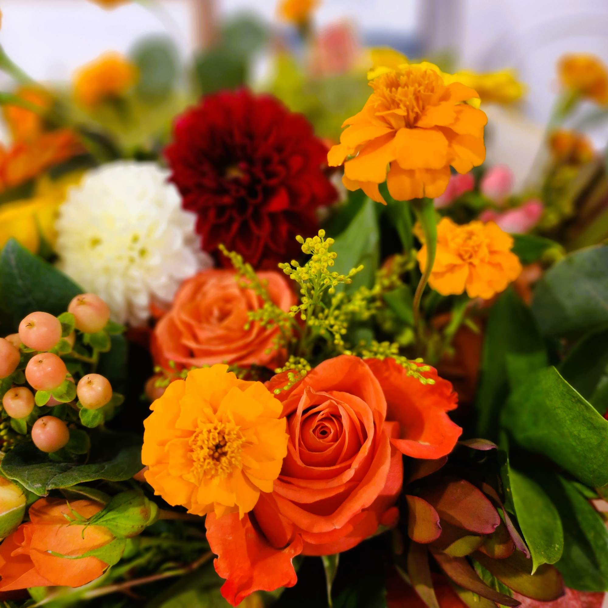 Mixed bouquet with orange roses, marigolds, and a white bloom