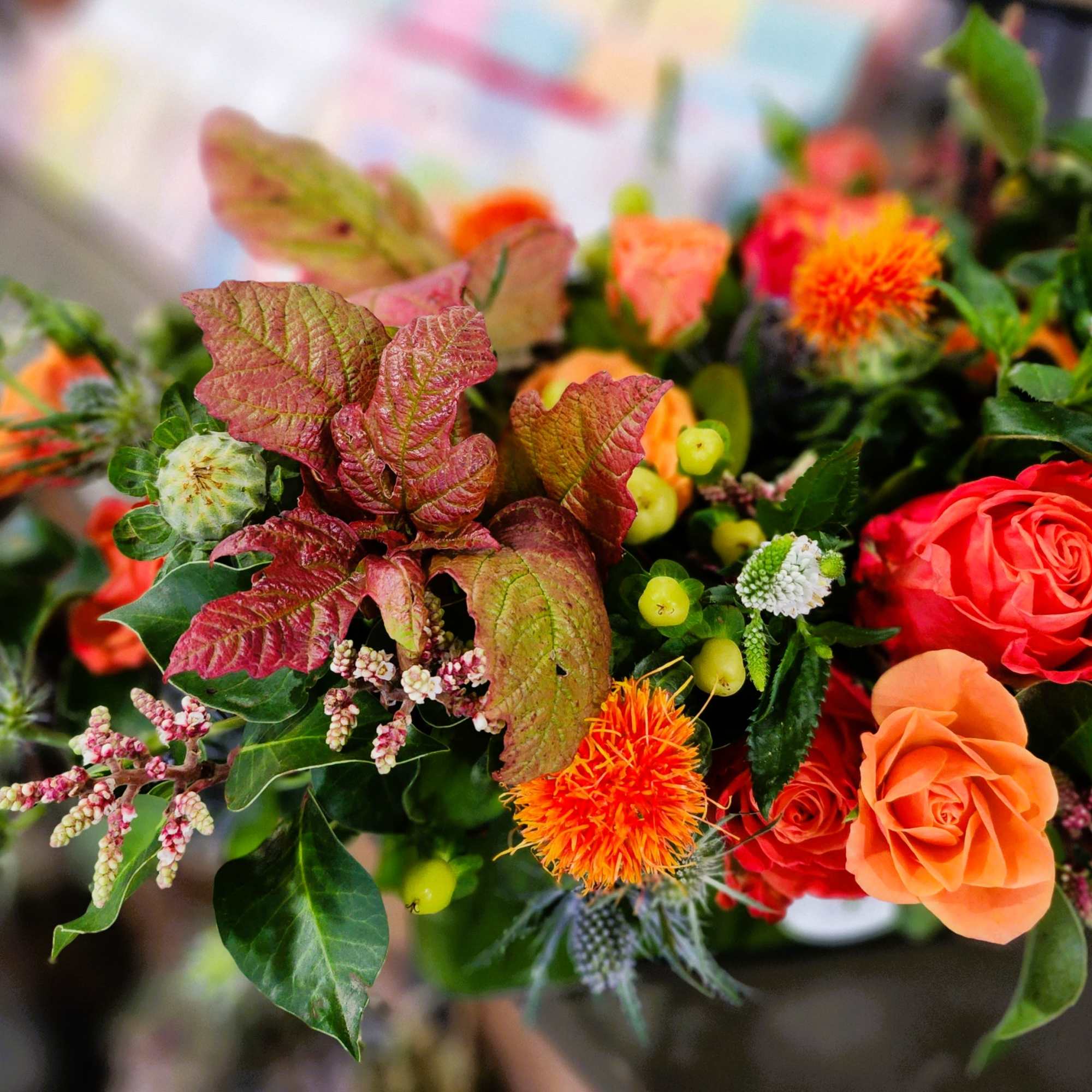 Mixed bouquet with orange and red roses and bright foliage