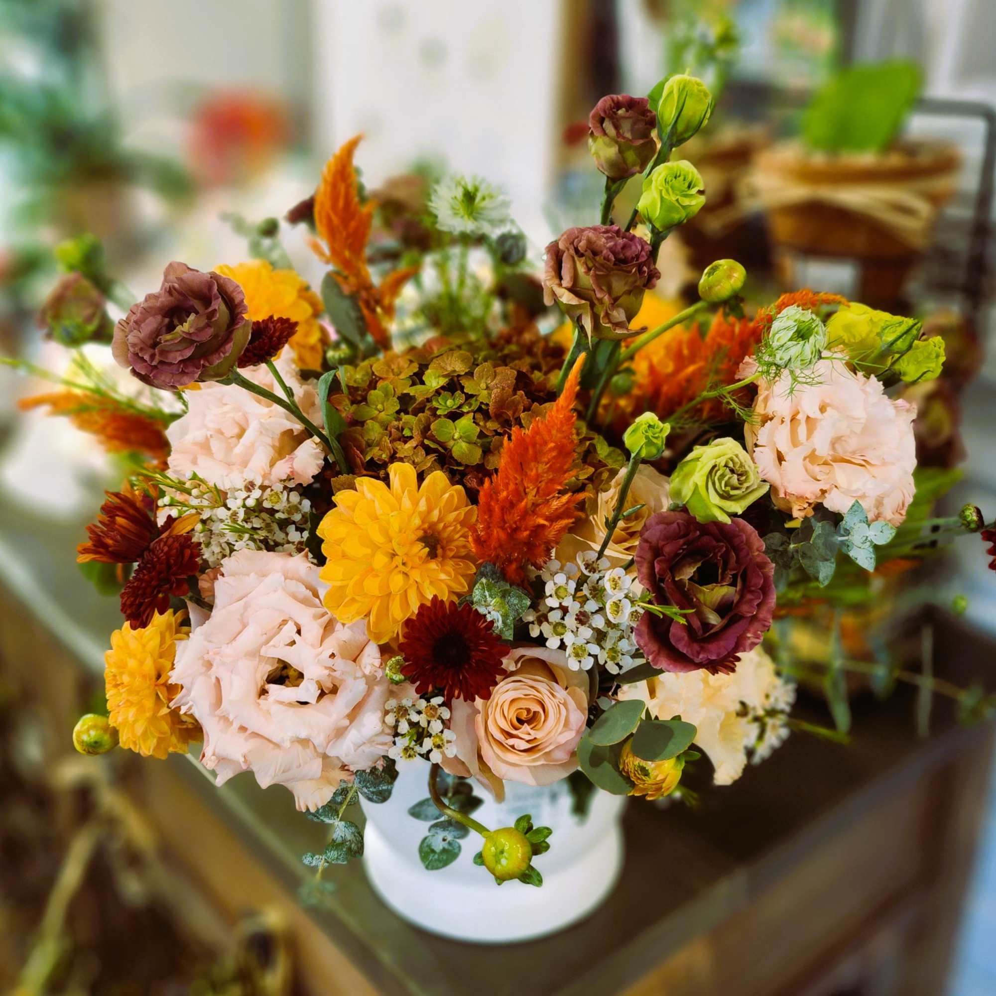 Mixed bouquet in a white vase with peach, yellow, and burgundy flowers