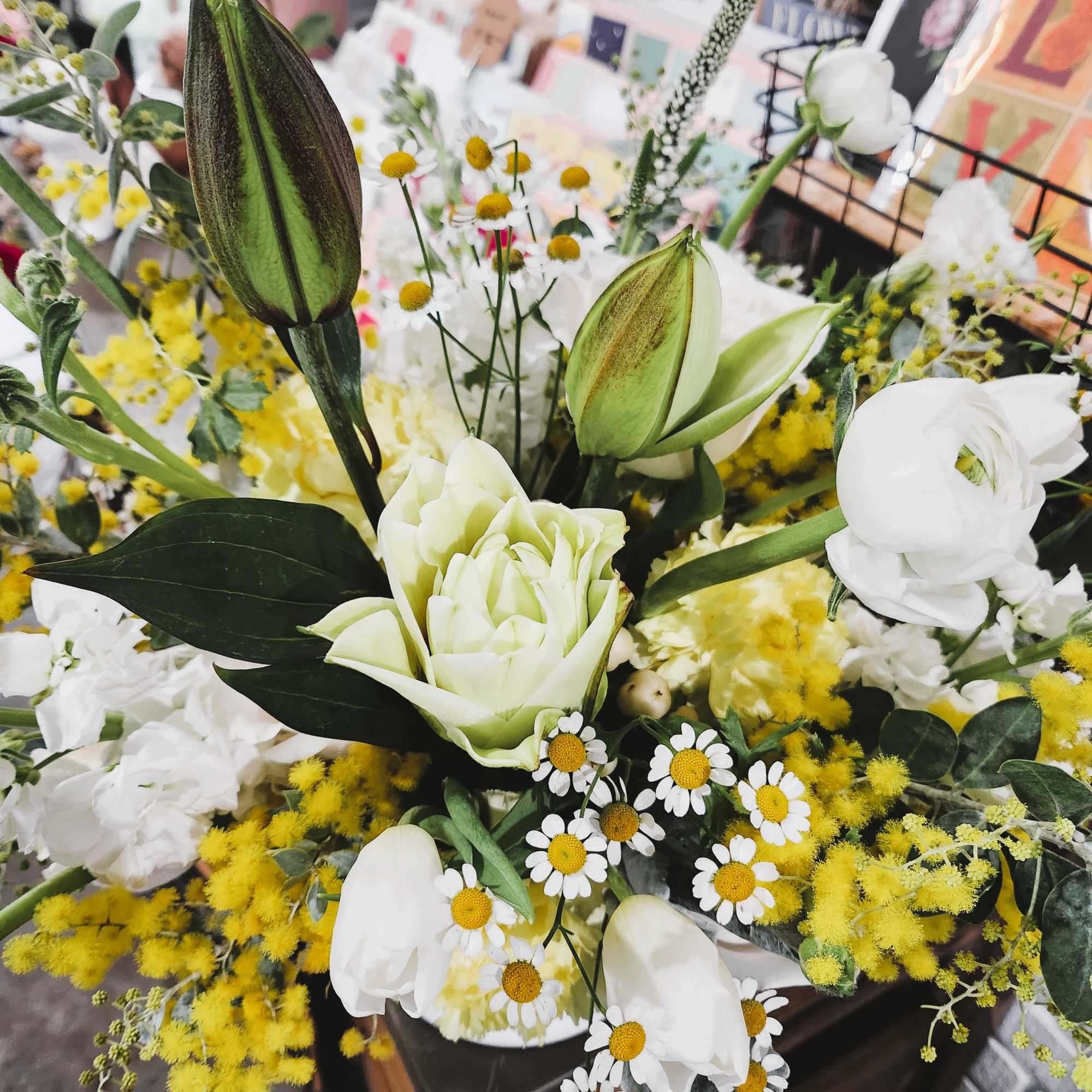 White lilies and daisies with yellow filler flowers in a bouquet