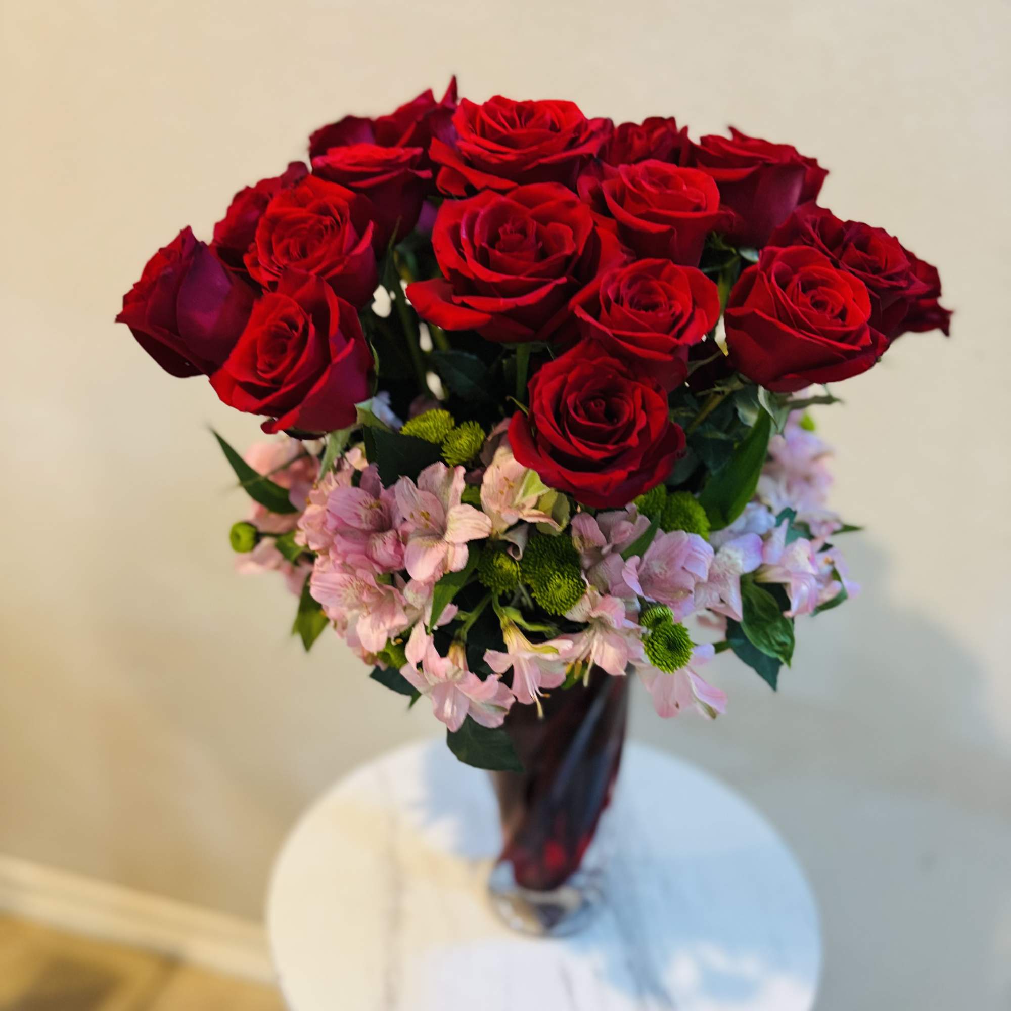 Bouquet of red roses with pink filler flowers in a glass vase