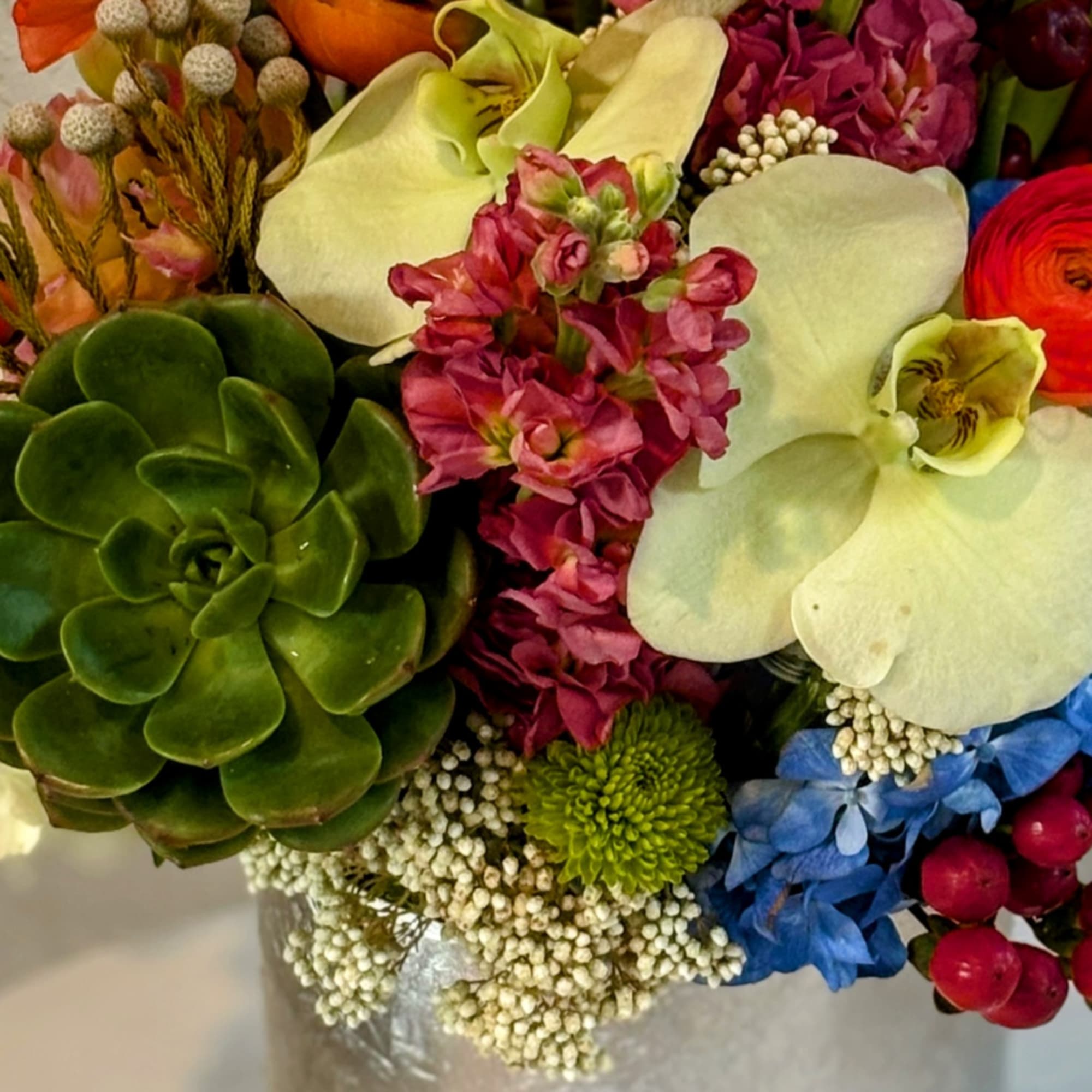 Mixed bouquet with white calla lilies, pink blooms, and a green succulent