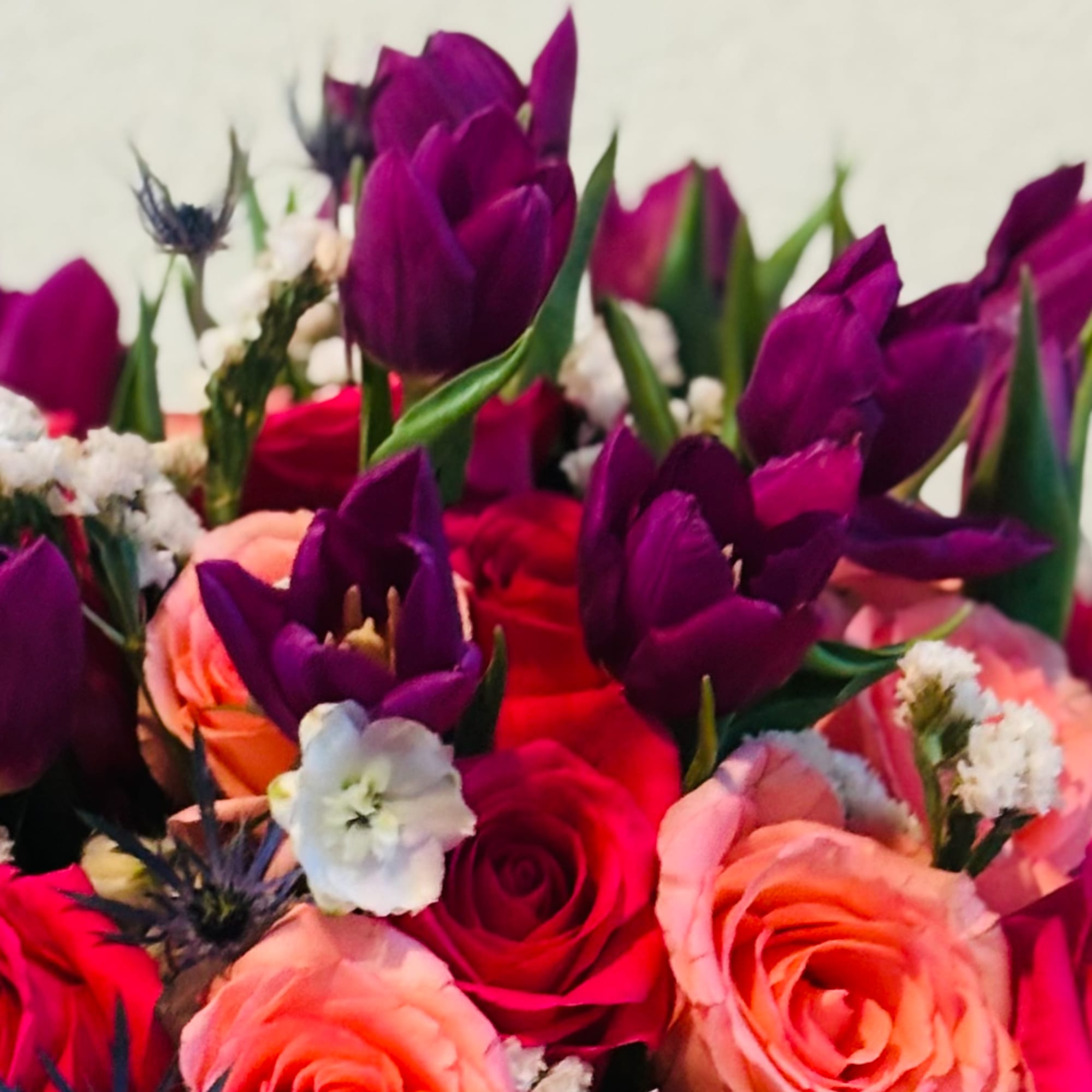 Bouquet of purple tulips and pink roses with small white filler flowers