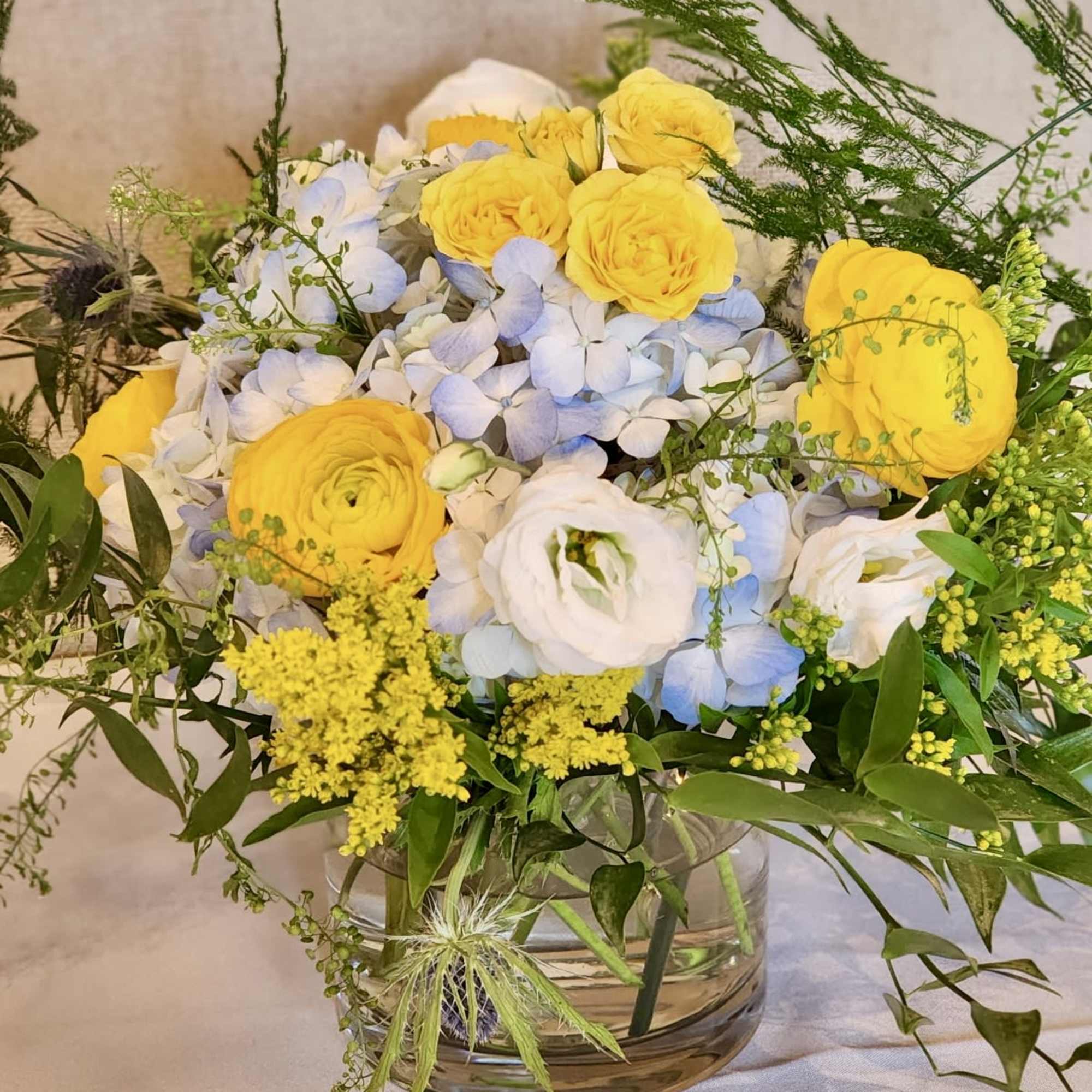 Yellow and white flowers arranged in a clear glass vase