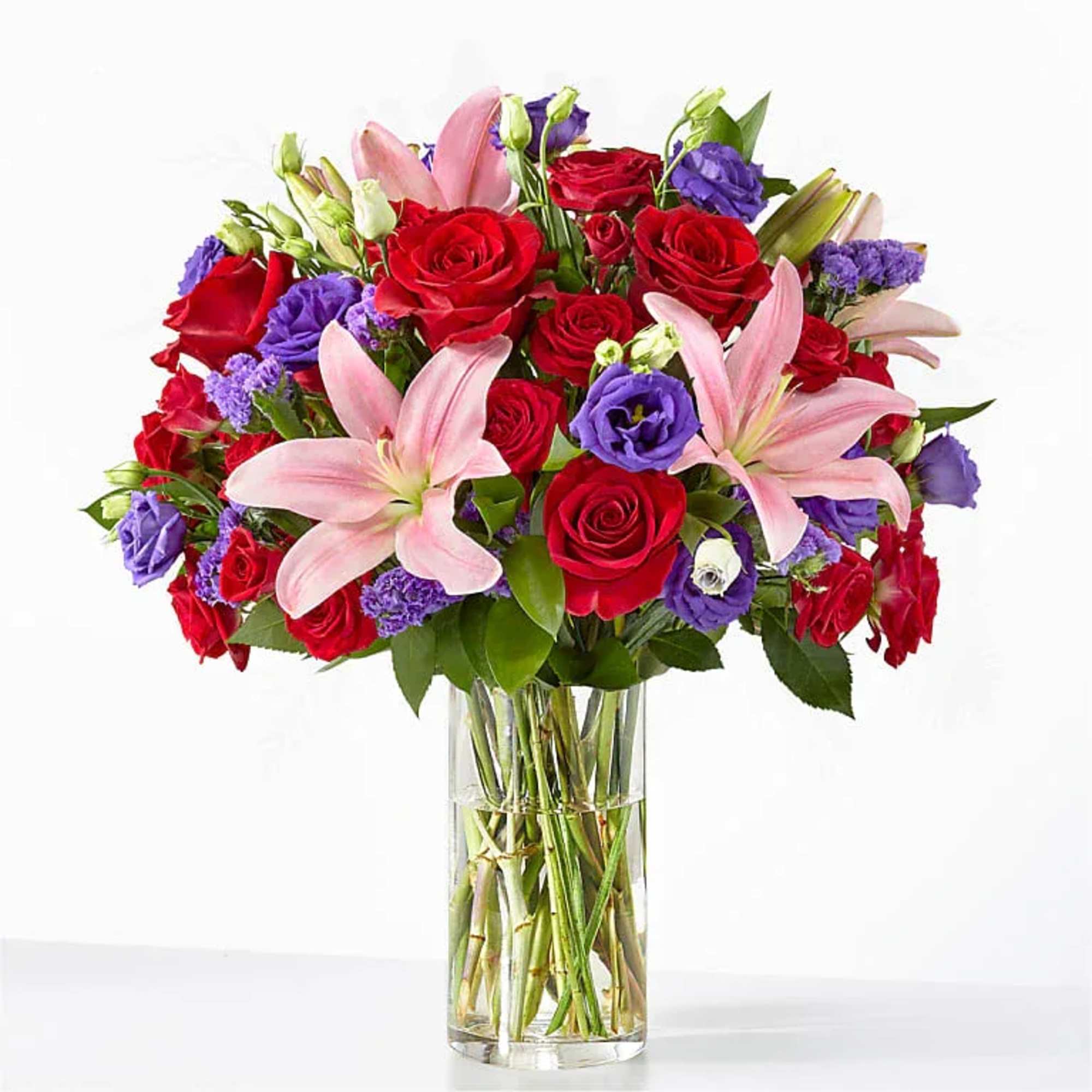 Striking red roses meet soft pink lilies in a full, rounded mixed