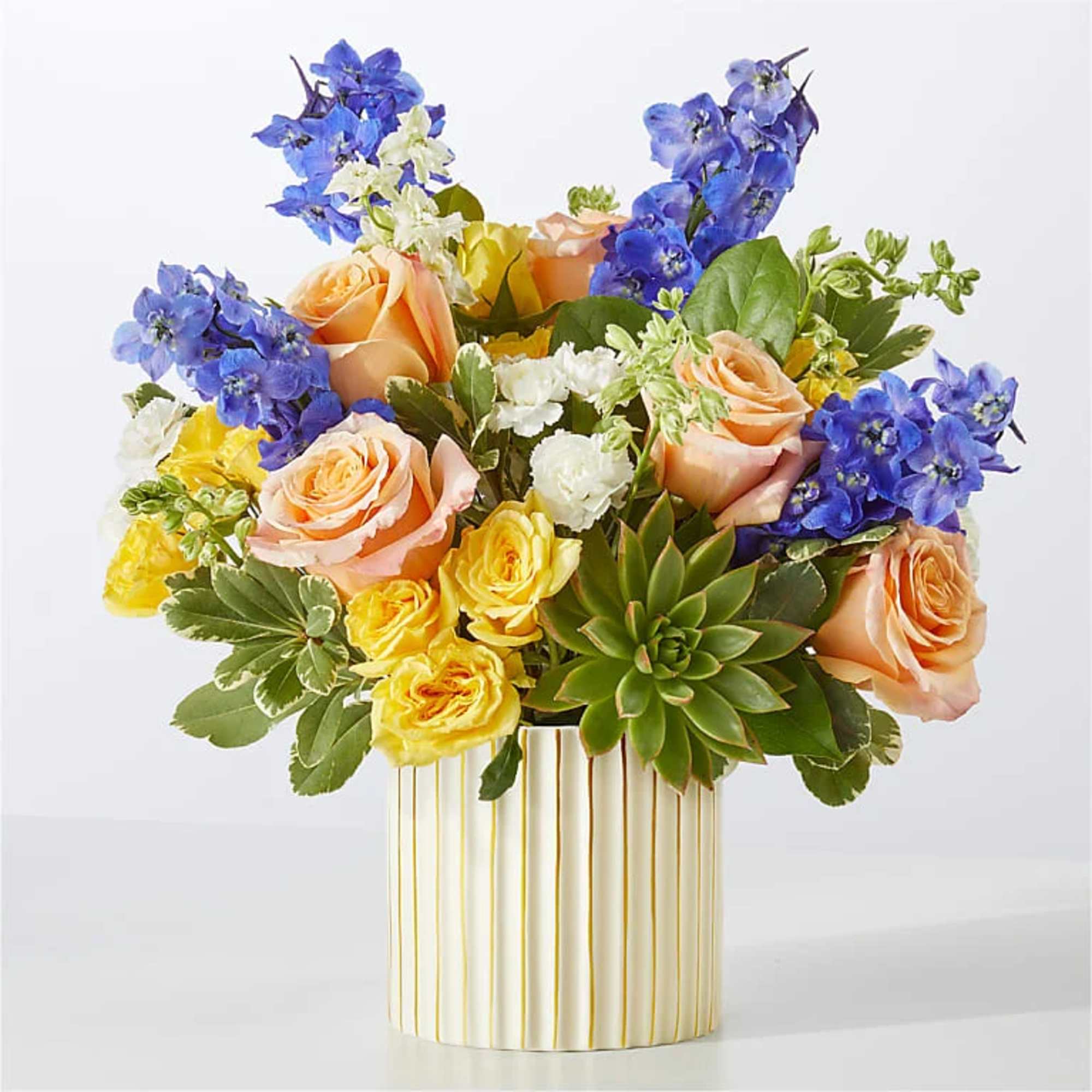 Mixed bouquet of pink and peach roses with white blooms in a striped vase