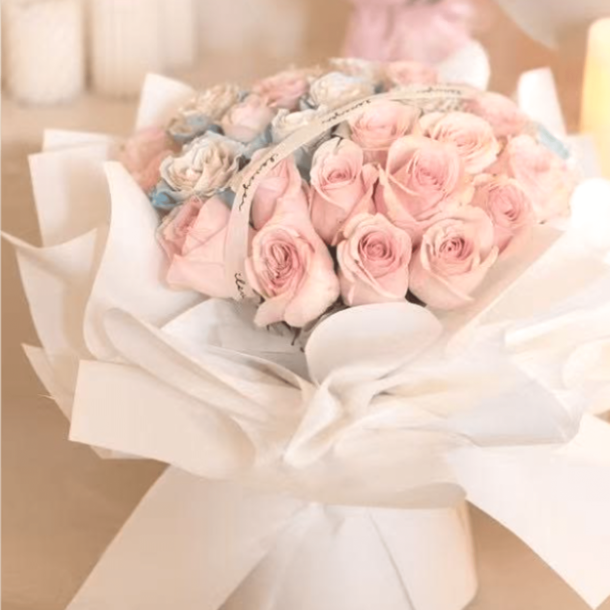 Bouquet of pale pink roses wrapped in white paper