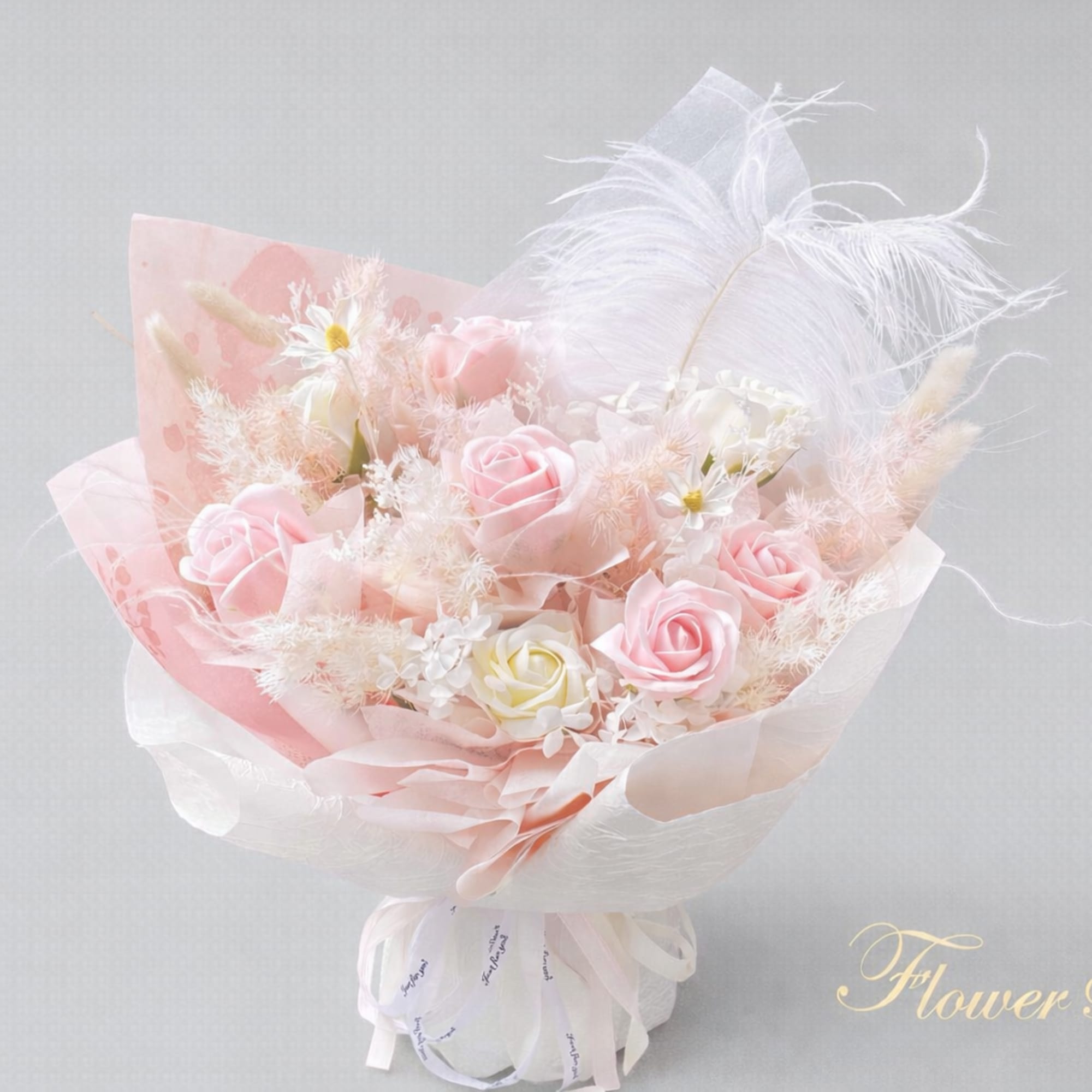 Pink and white rose bouquet with feathers and tissue wrap