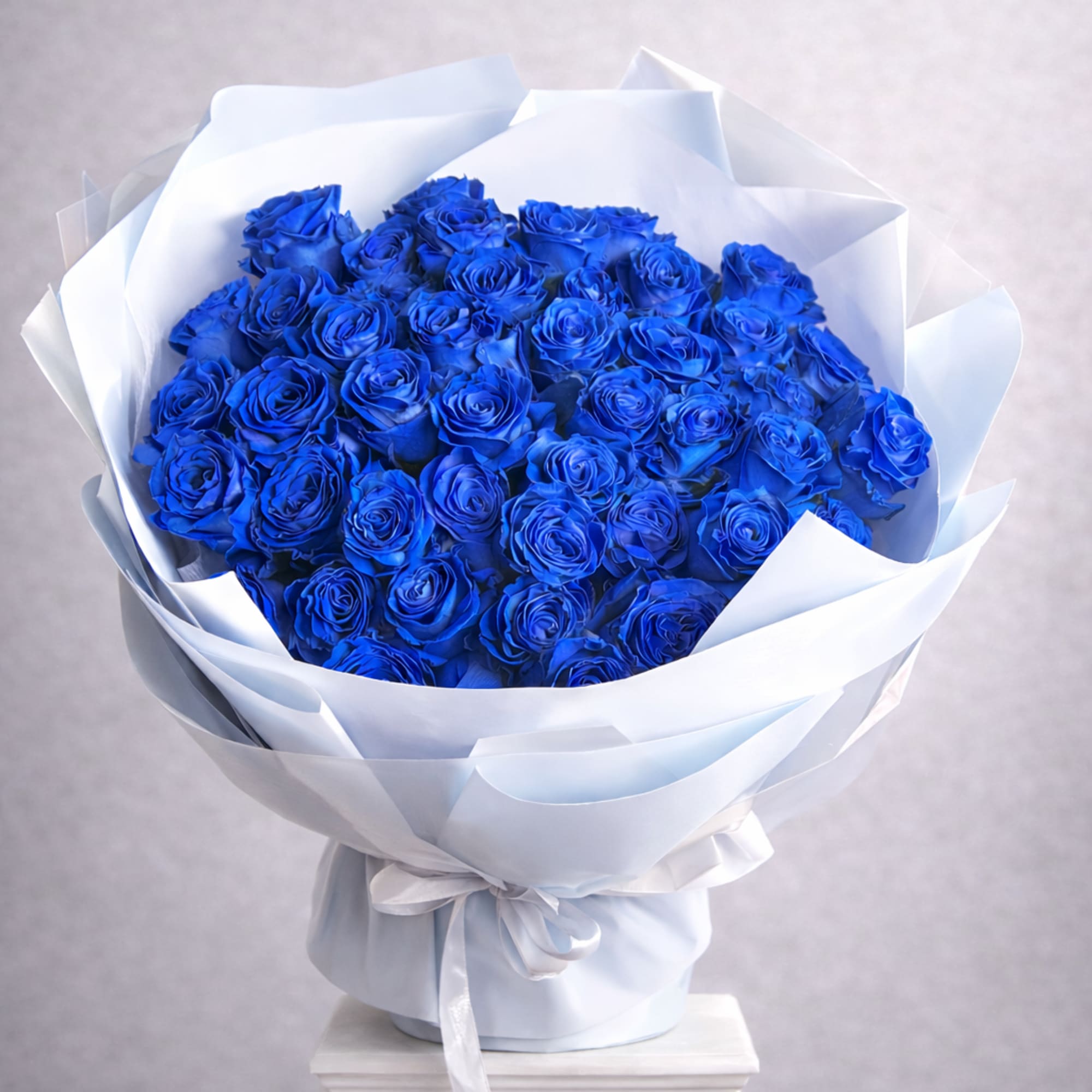 Bouquet of vivid blue roses wrapped in white paper