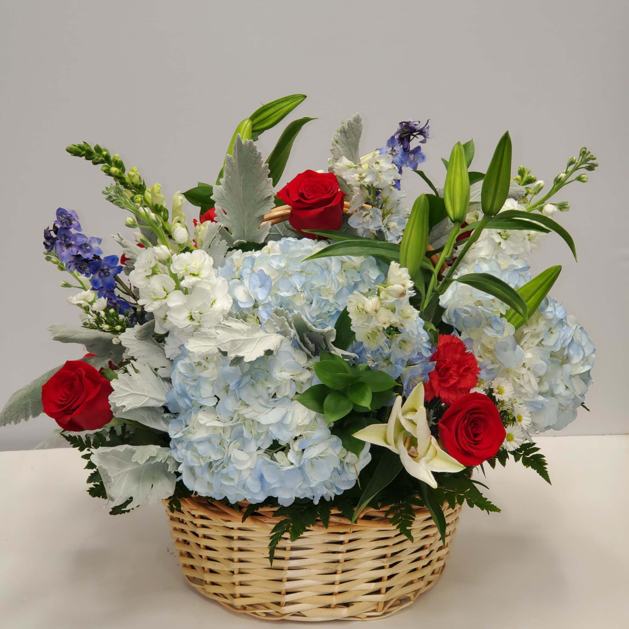7 red roses, 5 red carnations, 4 blue hydrangea, 4 blue delphinium