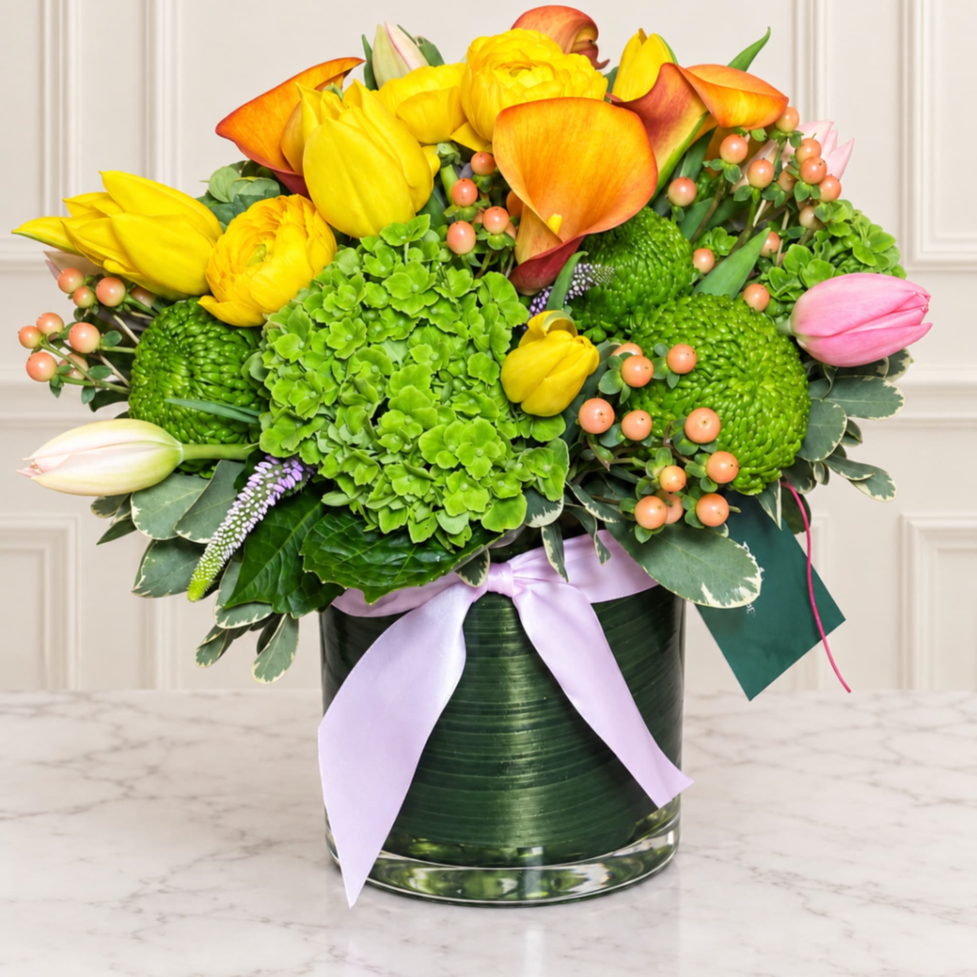 Bright bouquet of yellow and orange tulips with green blooms in a glass vase