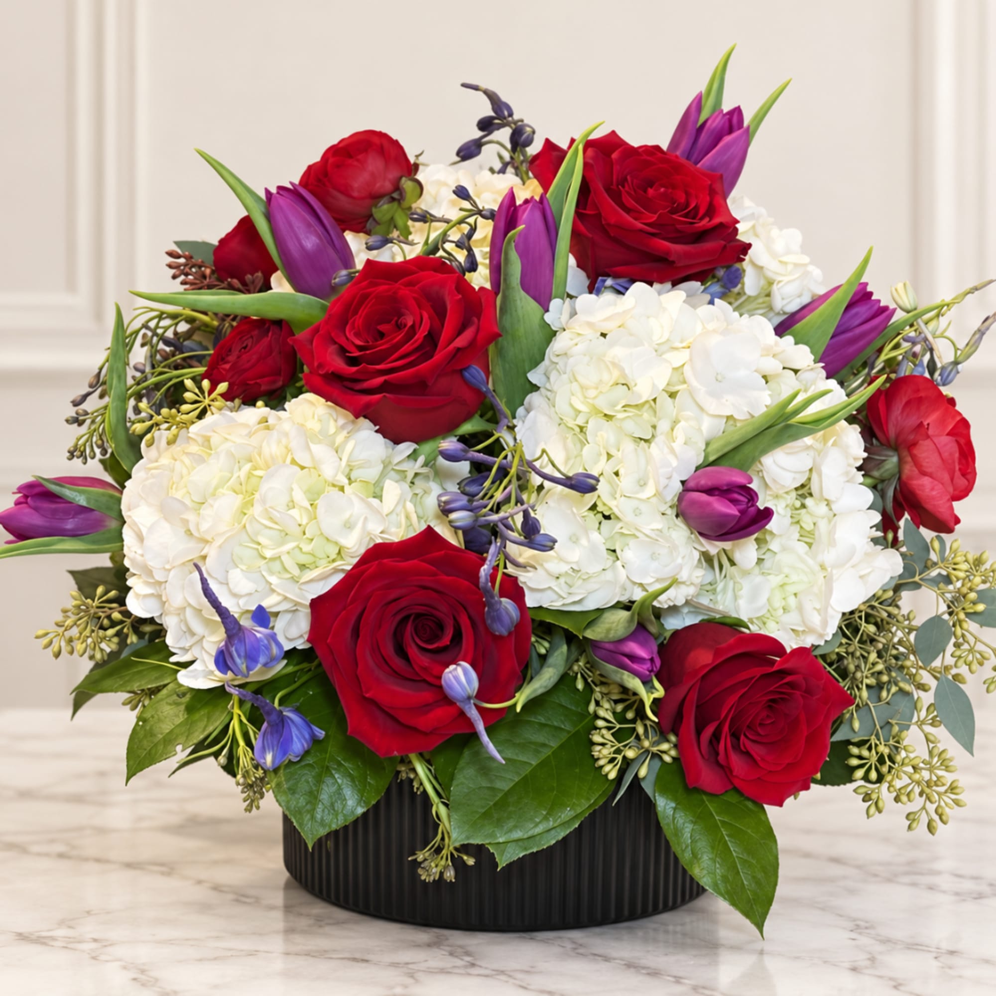Red roses and white hydrangeas in a black round container