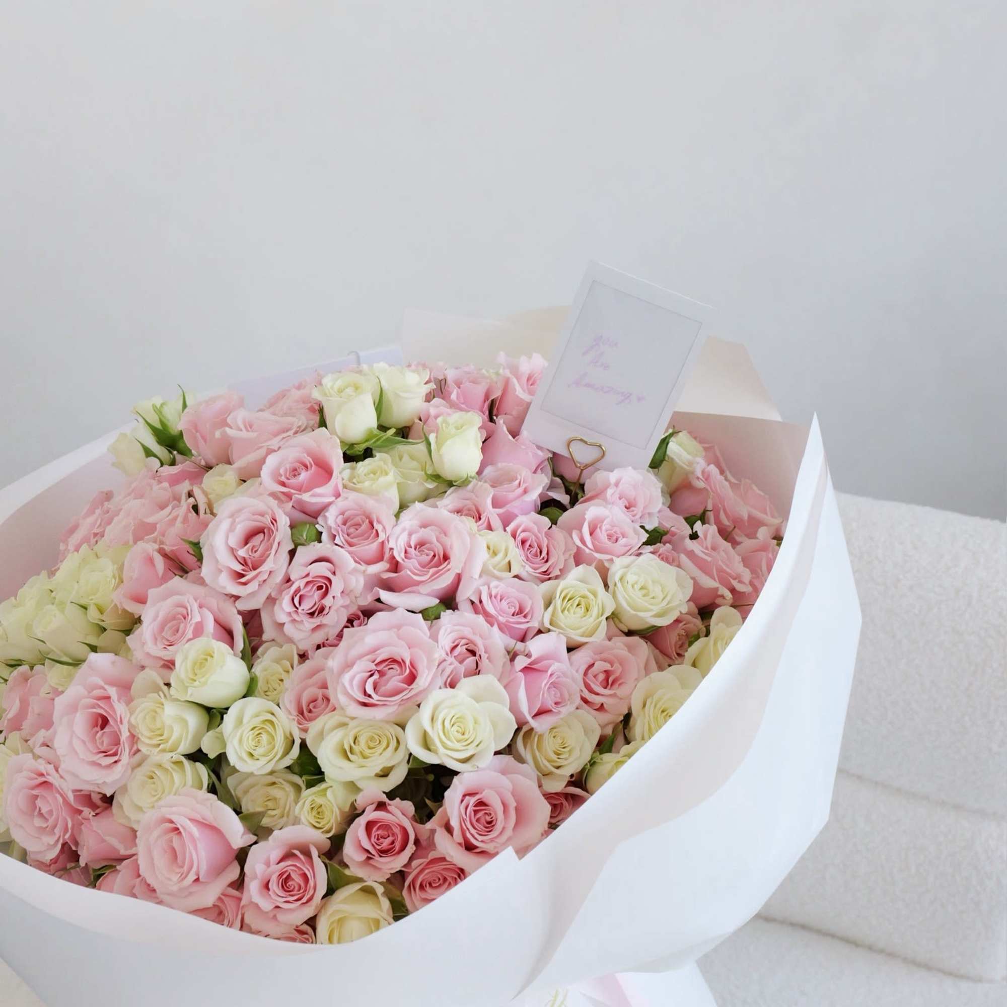 Large bouquet of pink and cream roses wrapped in white paper