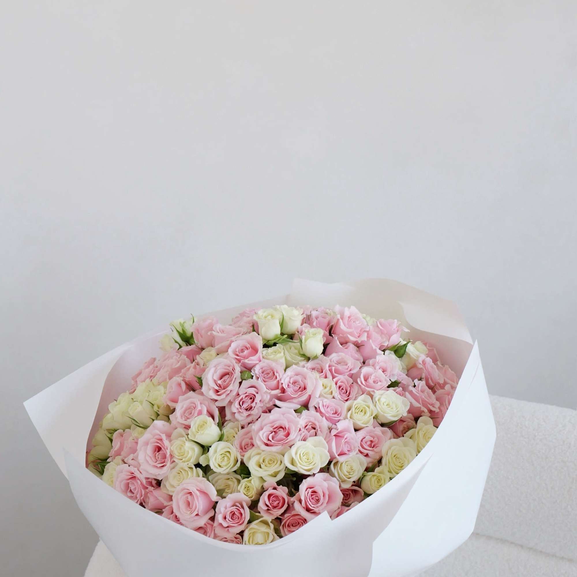 Large bouquet of pink and white roses wrapped in white paper