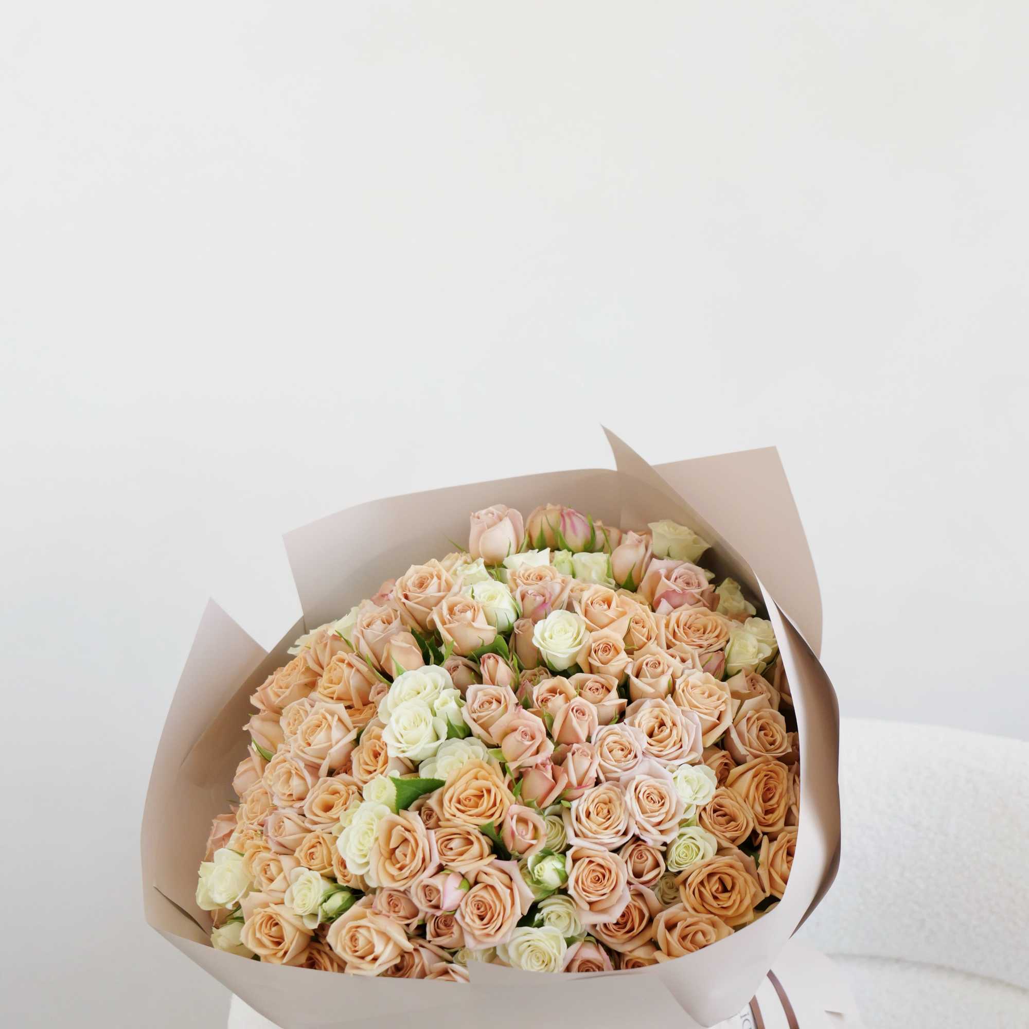 Large bouquet of peach and cream roses wrapped in beige paper, photo 2 of 2