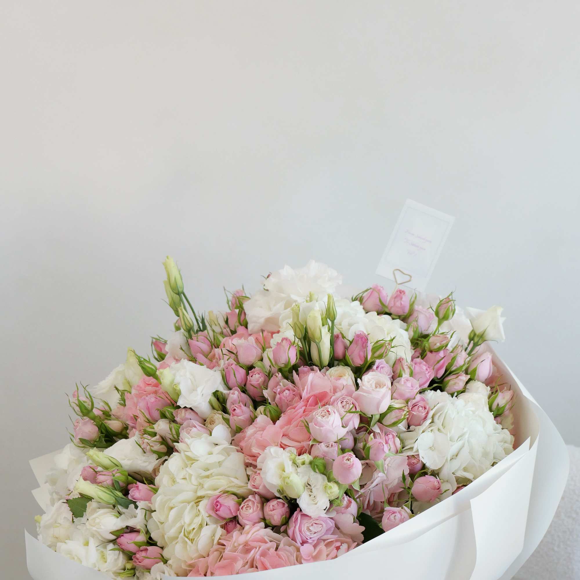 Large bouquet of pink and white roses wrapped in white paper