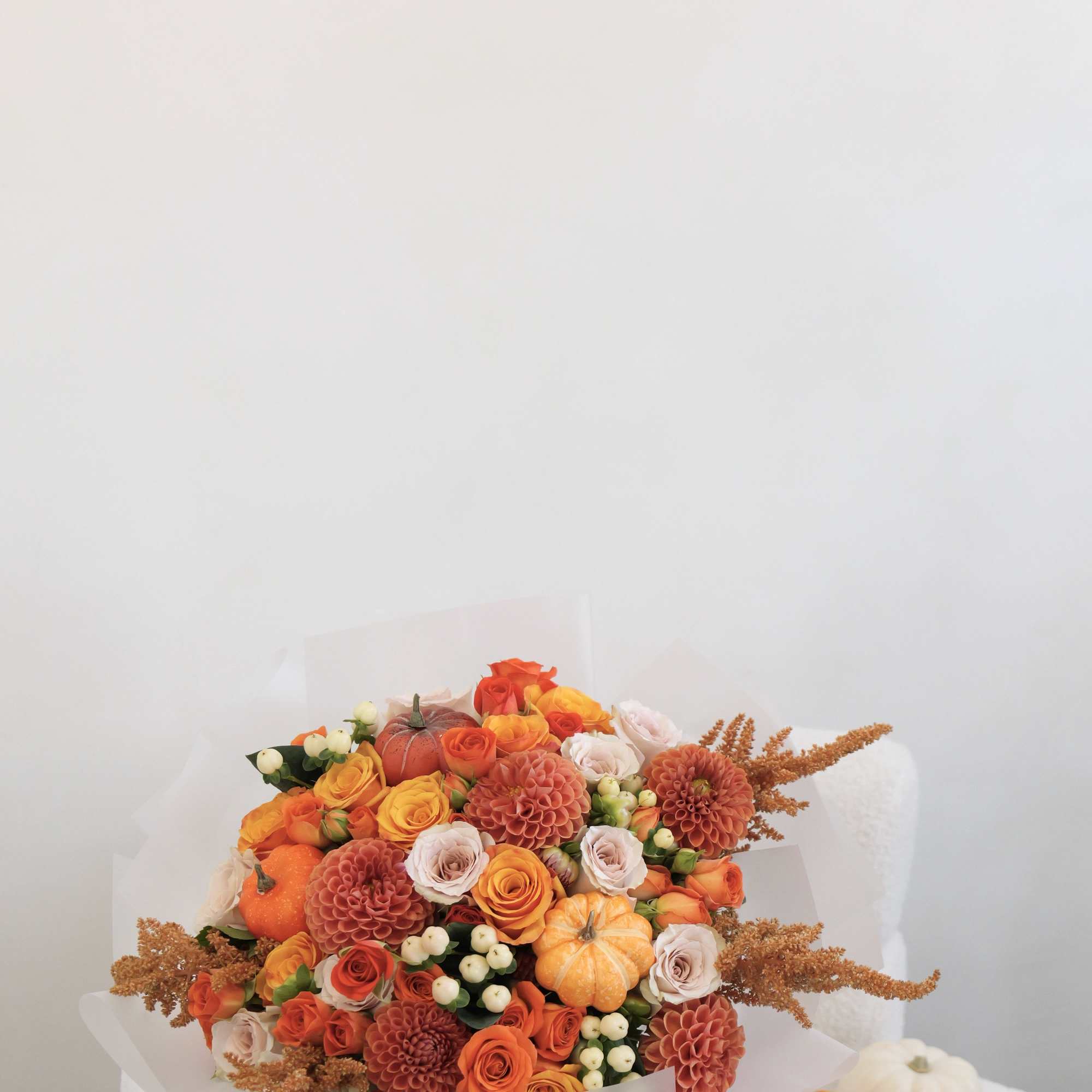 Bouquet of orange and peach roses with small pumpkins