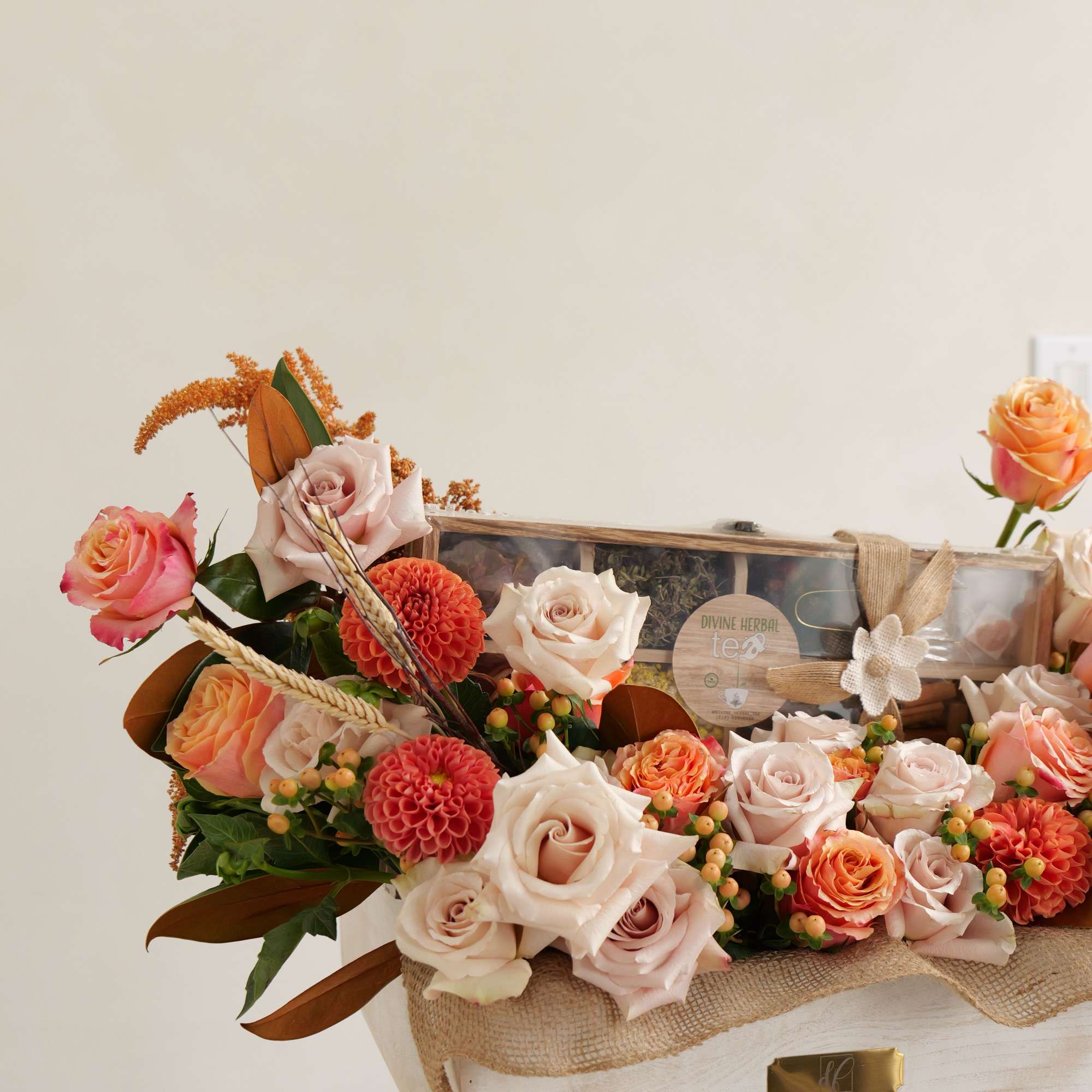 Mixed roses and orange dahlias arranged in a wooden gift box