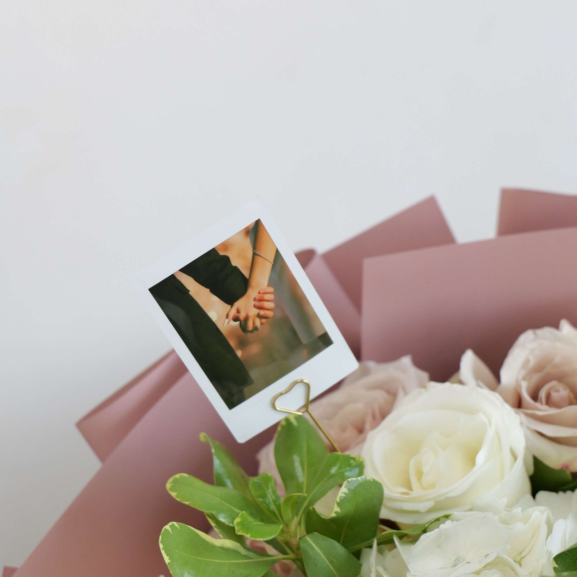Bouquet of white and blush roses with hydrangeas and a small photo card