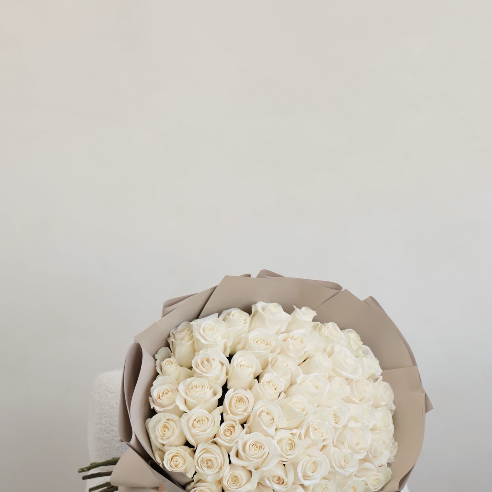 Bouquet of white roses wrapped in beige paper
