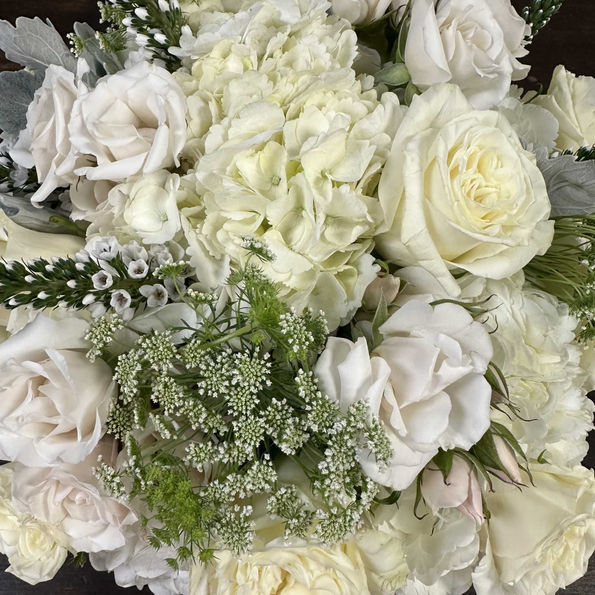 White roses and hydrangeas with small white filler flowers in a bouquet