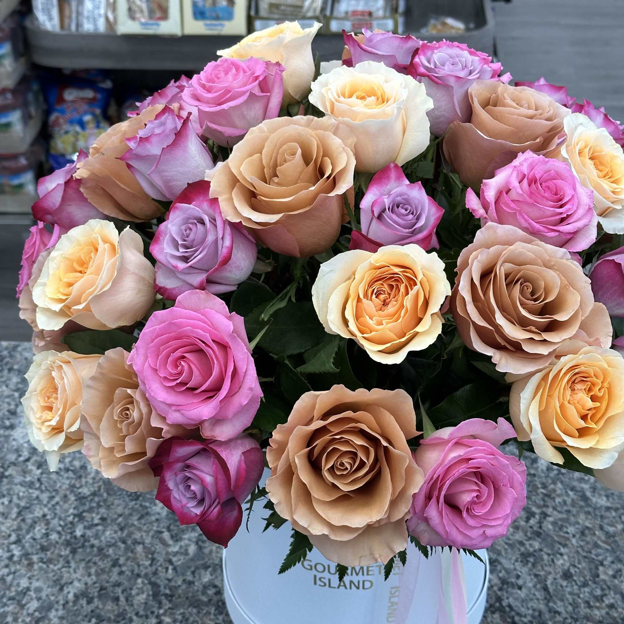 Bouquet of pink, peach, and lavender roses in a white hat box