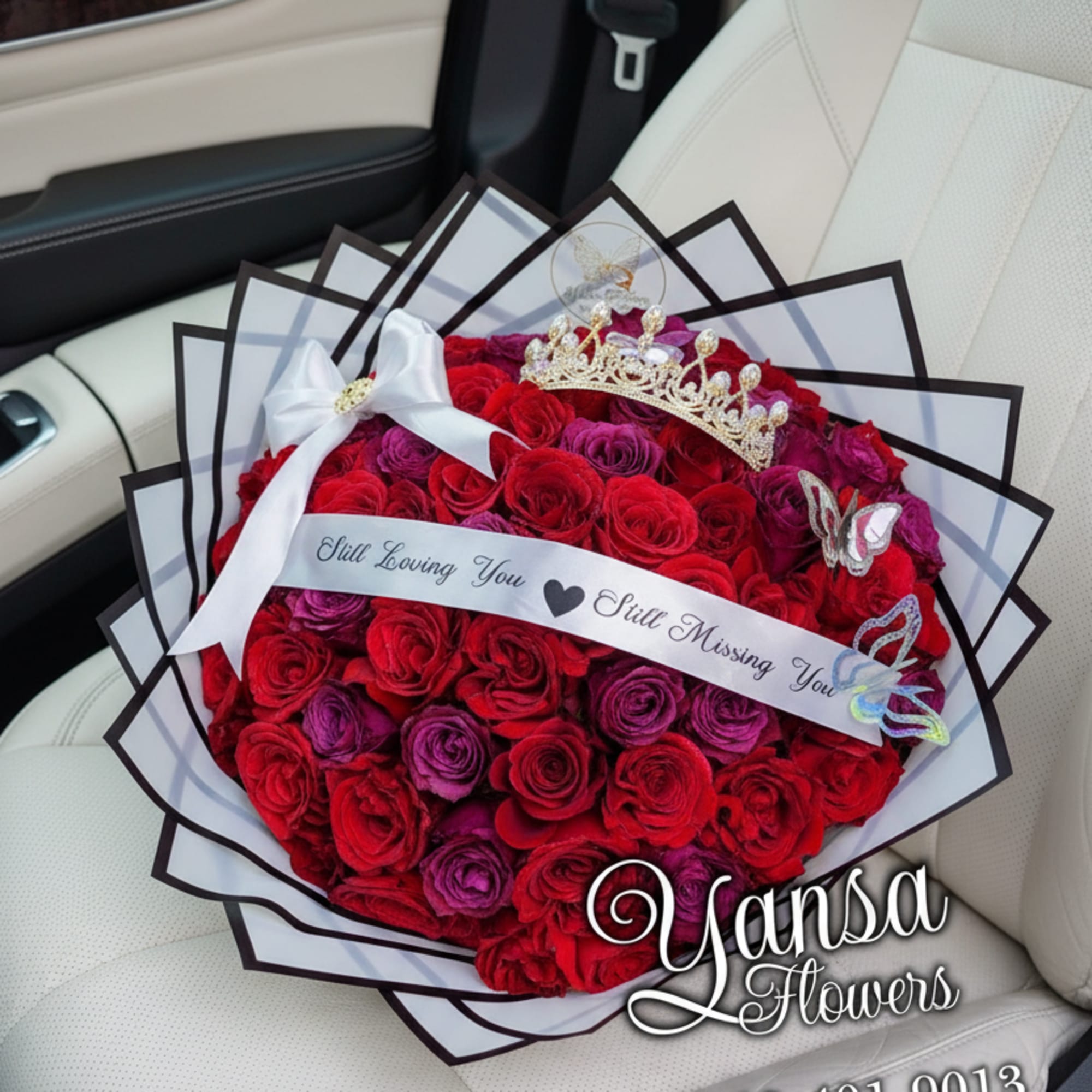 A stunning blend of red and purple roses wrapped in crisp white