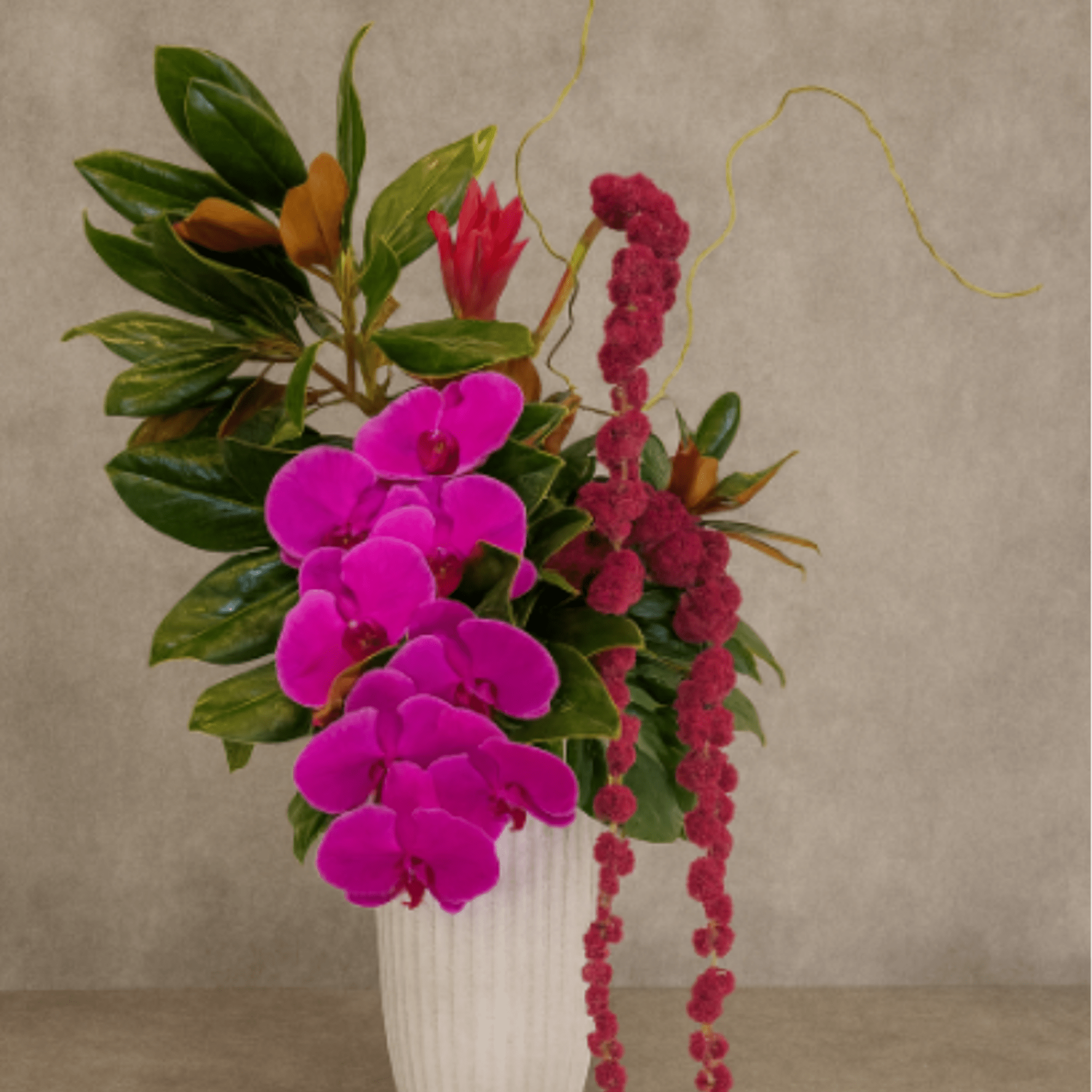 Pink orchids and red hanging blooms in a white vase