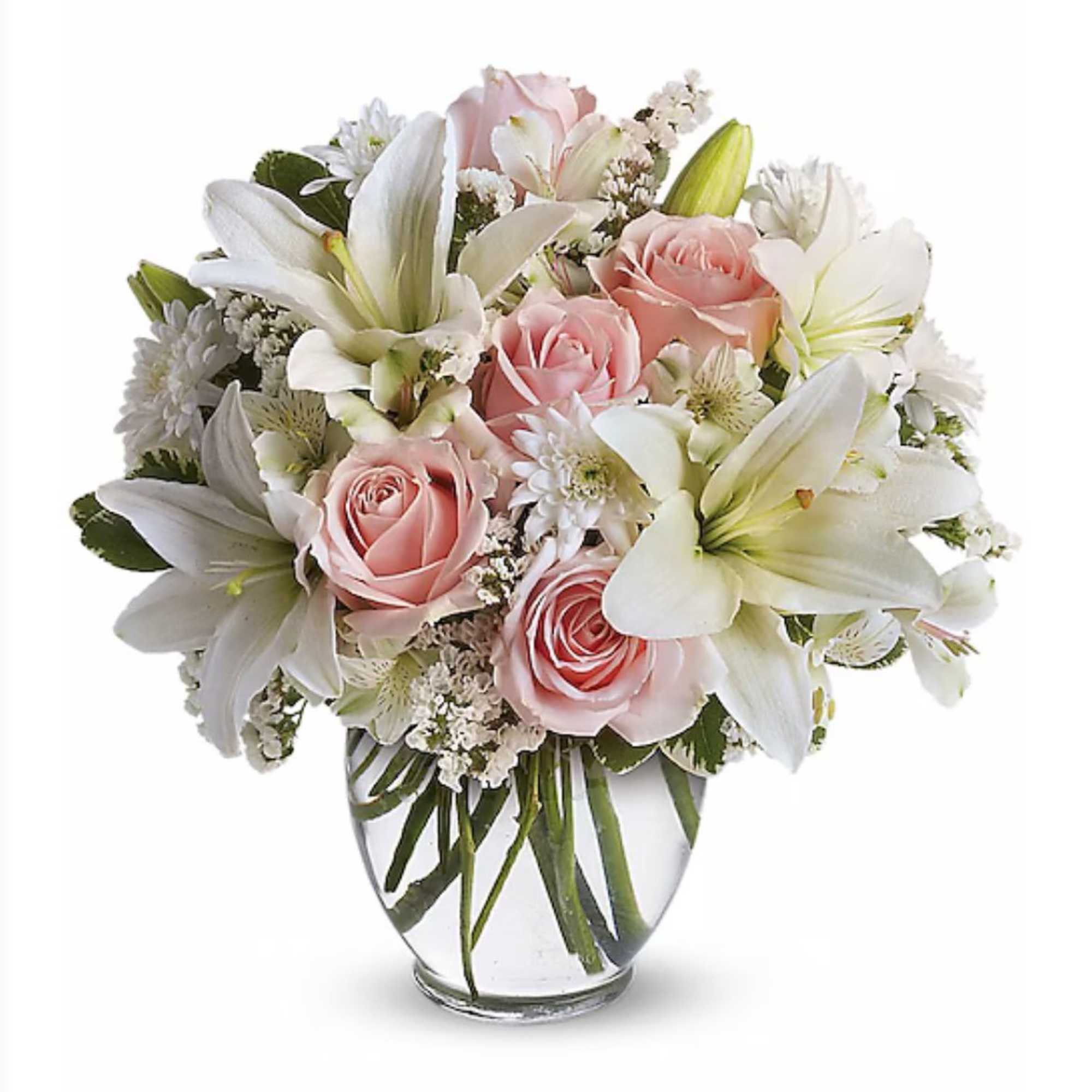 Round bouquet of white lilies and soft pink roses in a clear glass vase