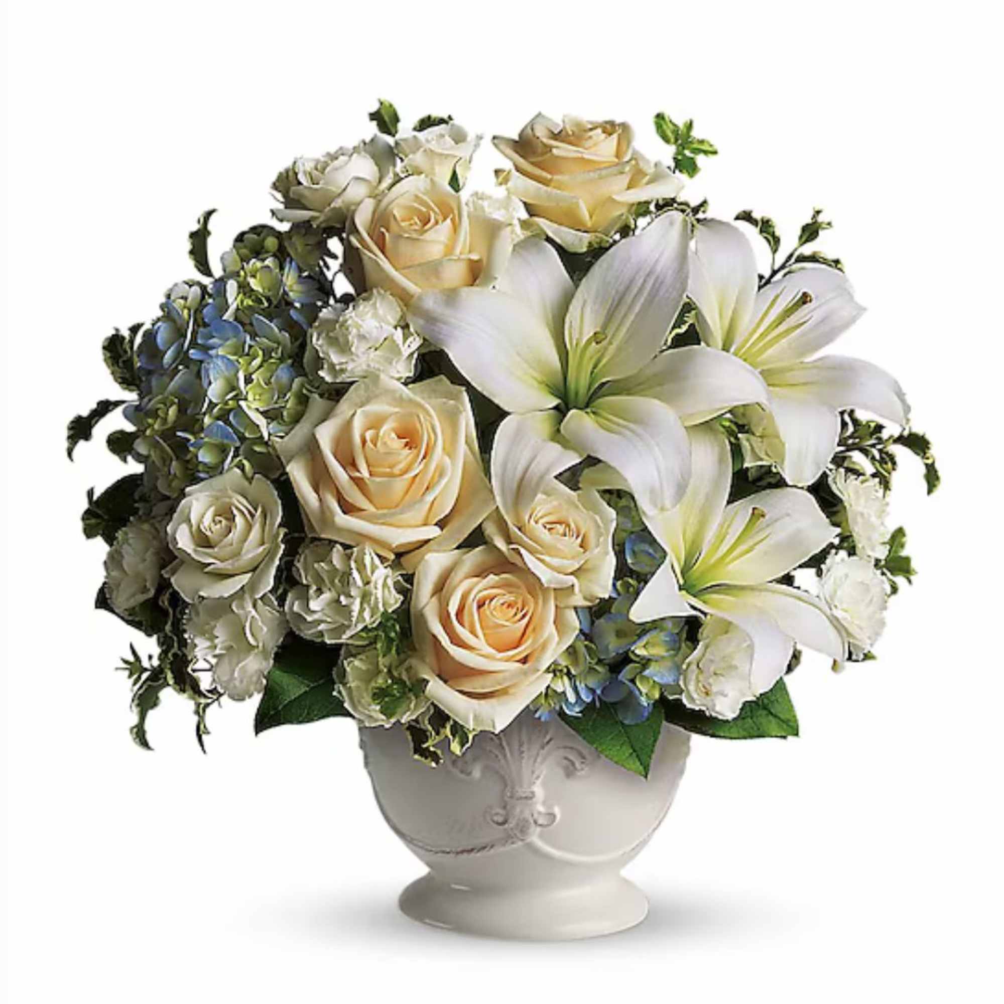 Round arrangement of white lilies, cream roses, and blue blooms in a white pedestal bowl