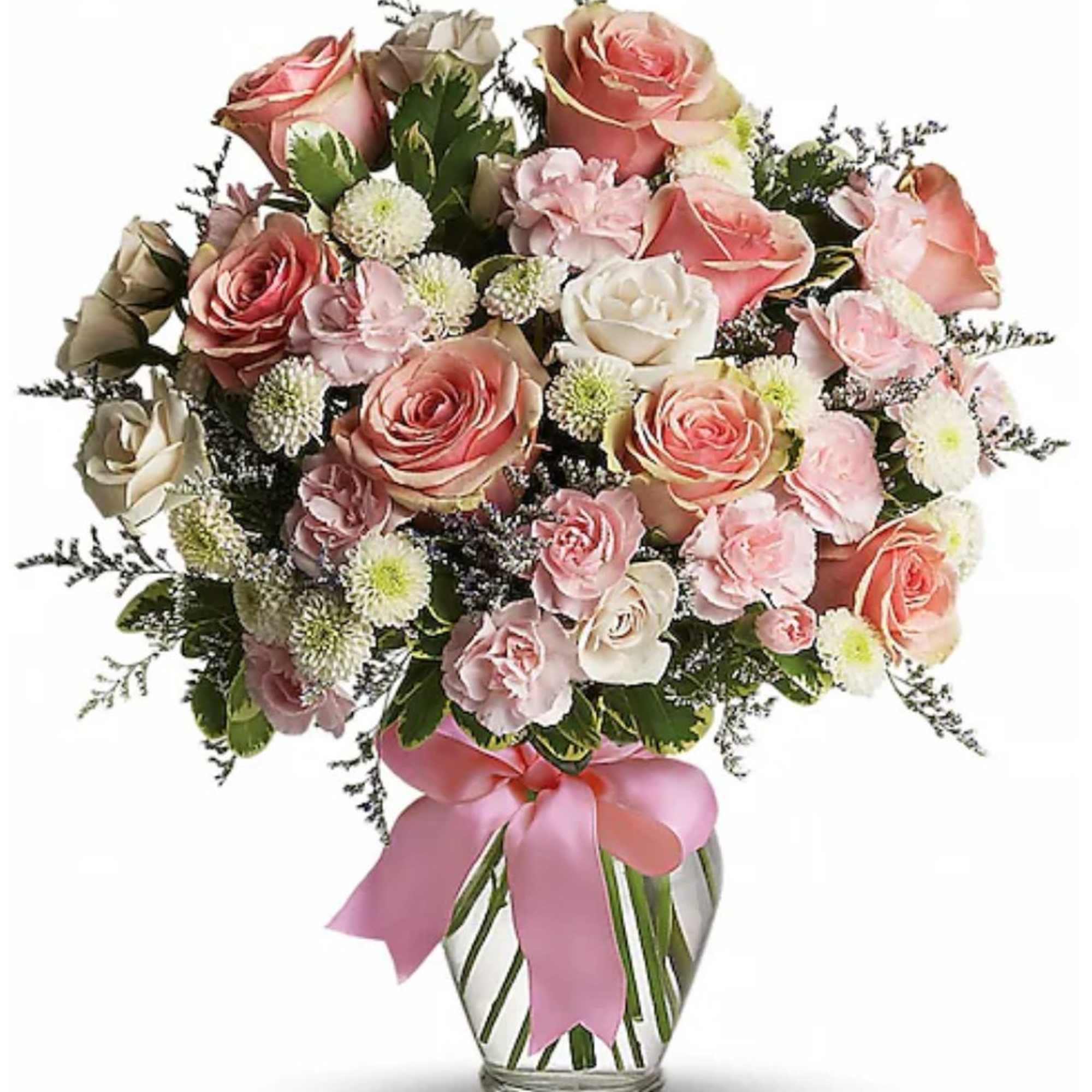 Pink and cream roses, carnations, and white button poms in a clear glass vase with a pink ribbon