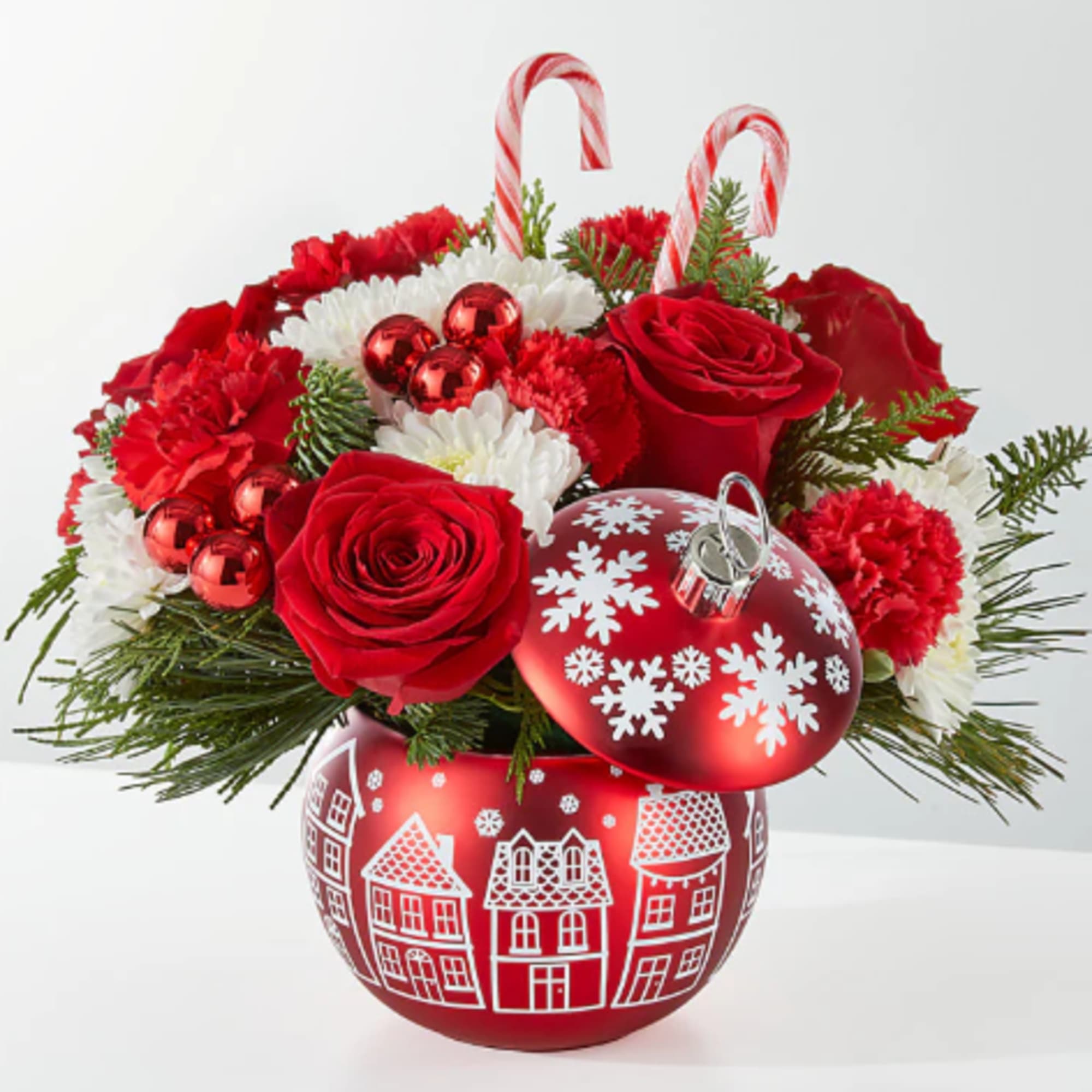 Red and white floral arrangement in a red holiday ornament vase with candy canes