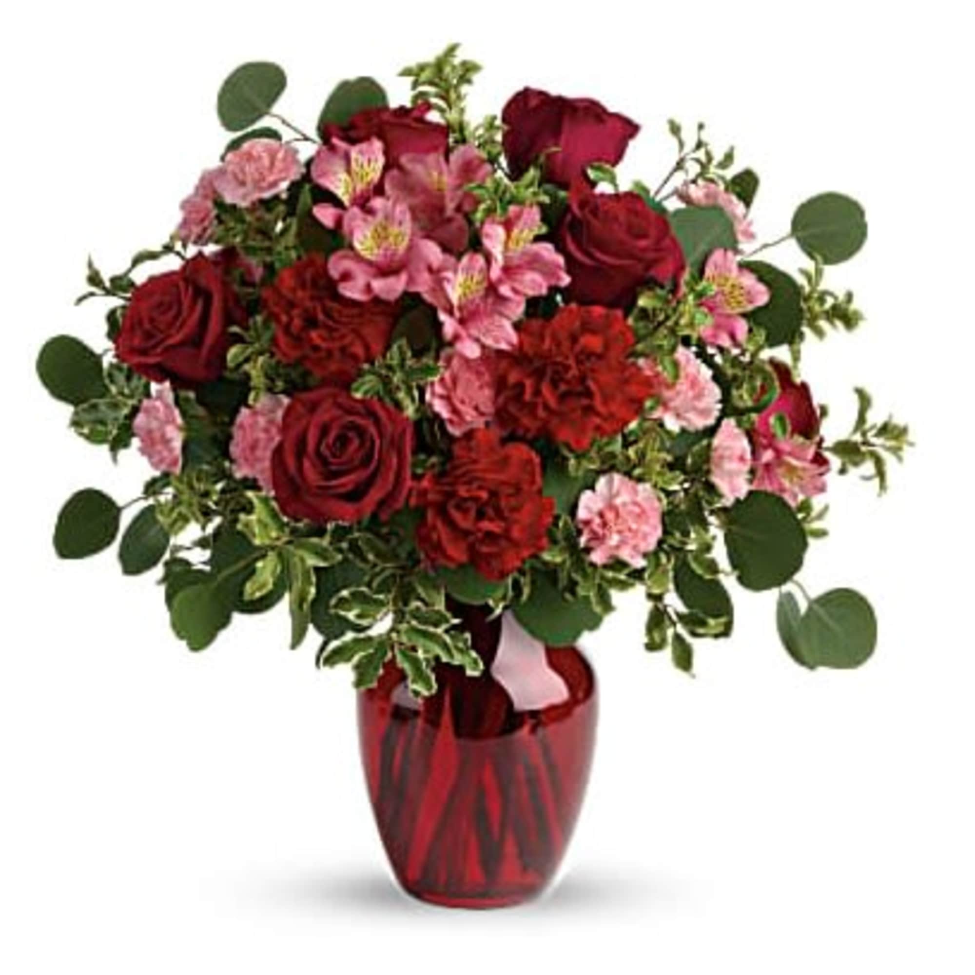 Red roses and pink flowers in a red glass vase