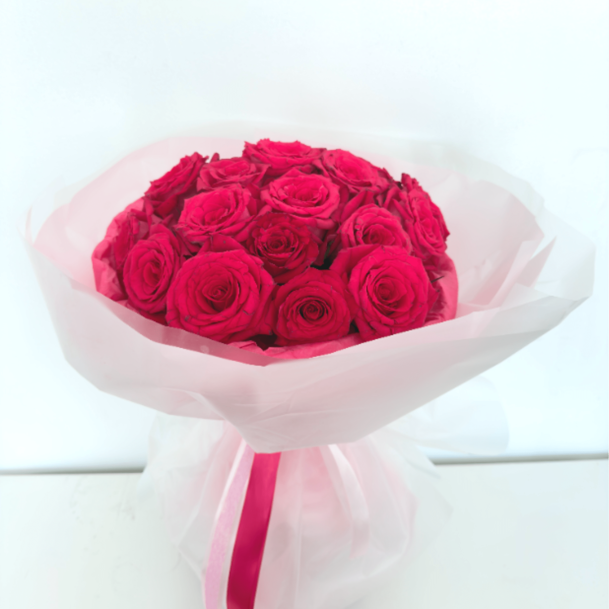 Bouquet of bright pink roses wrapped in pale pink paper