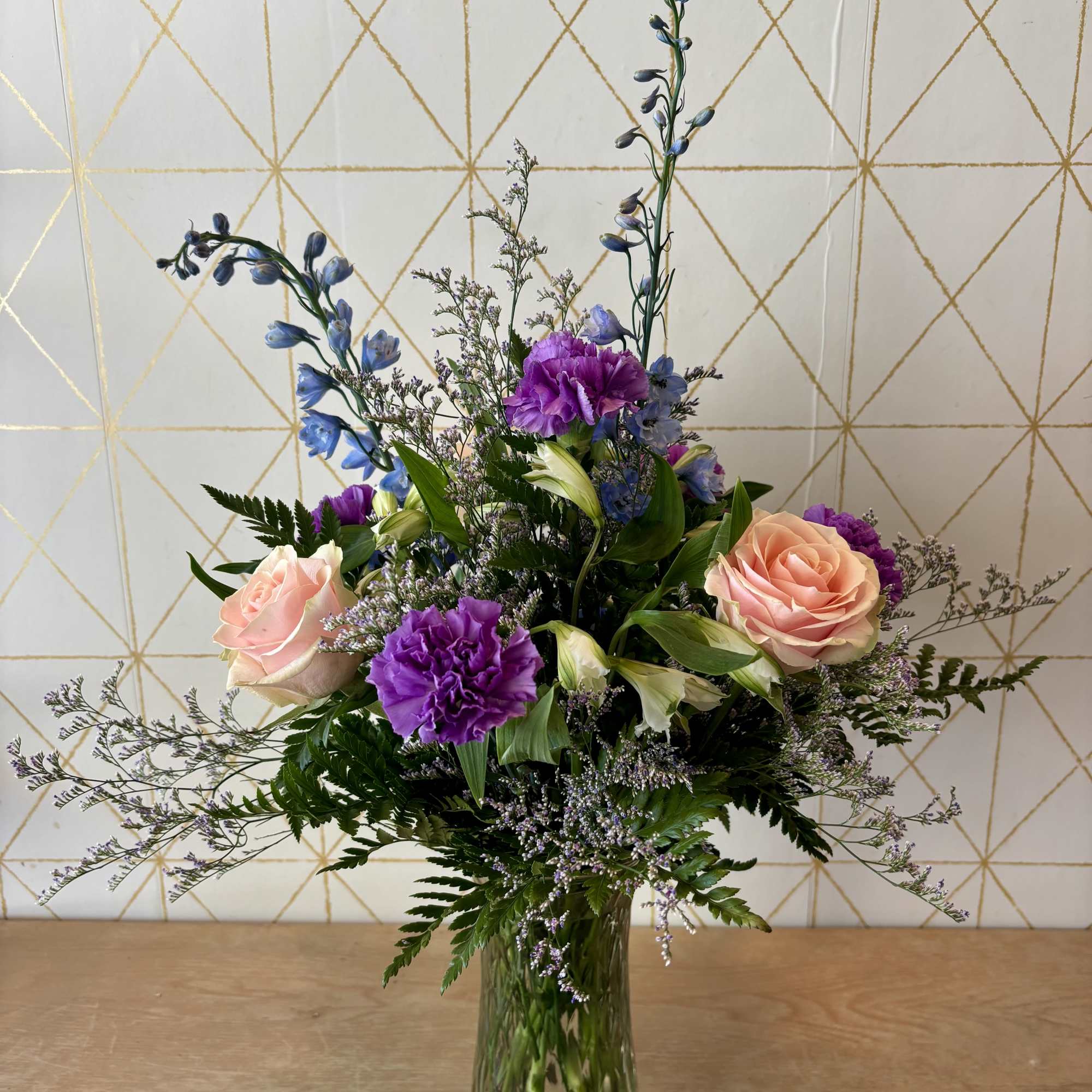 Mixed bouquet of pink roses and purple flowers in a glass vase