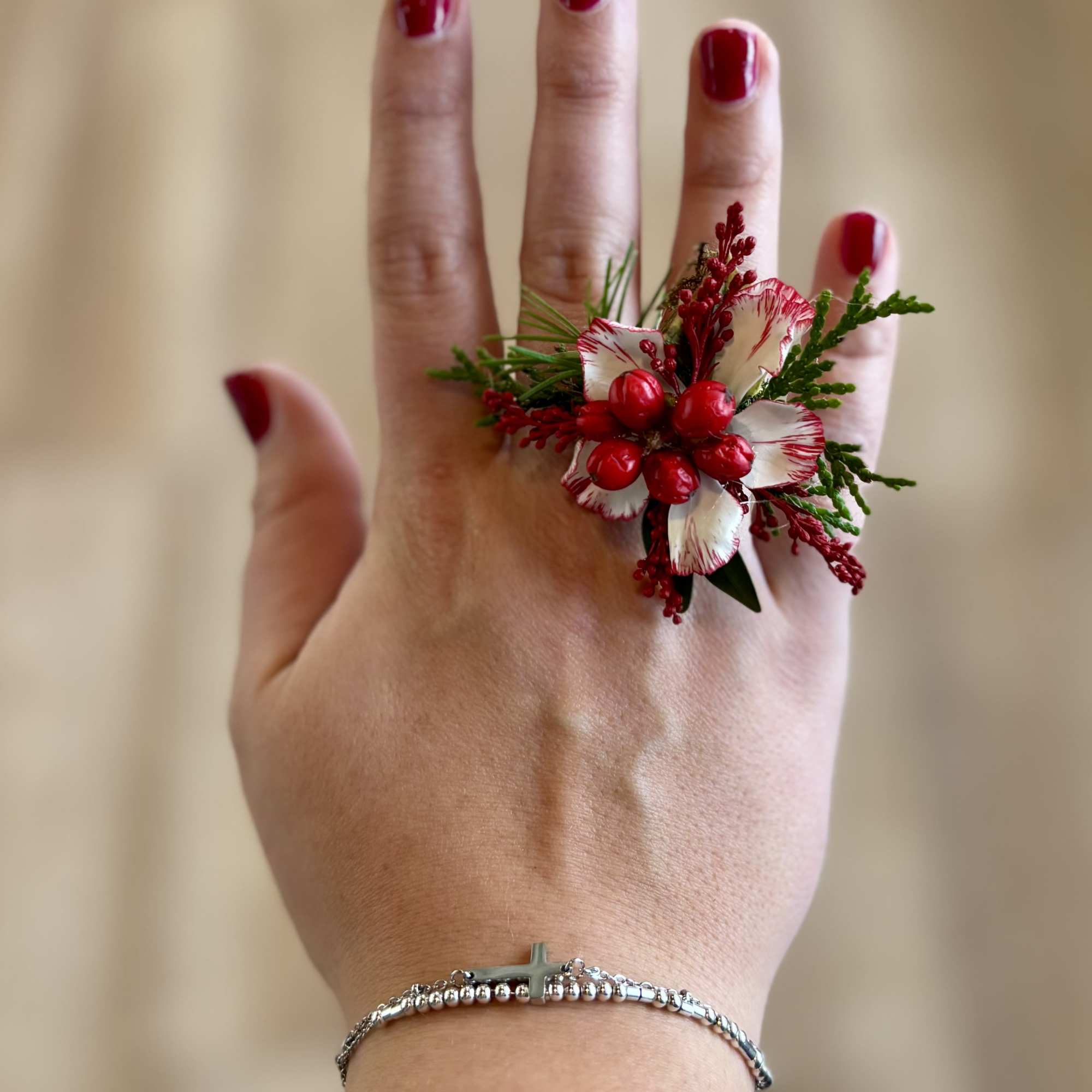Hand wearing a red and white floral ring with berries
