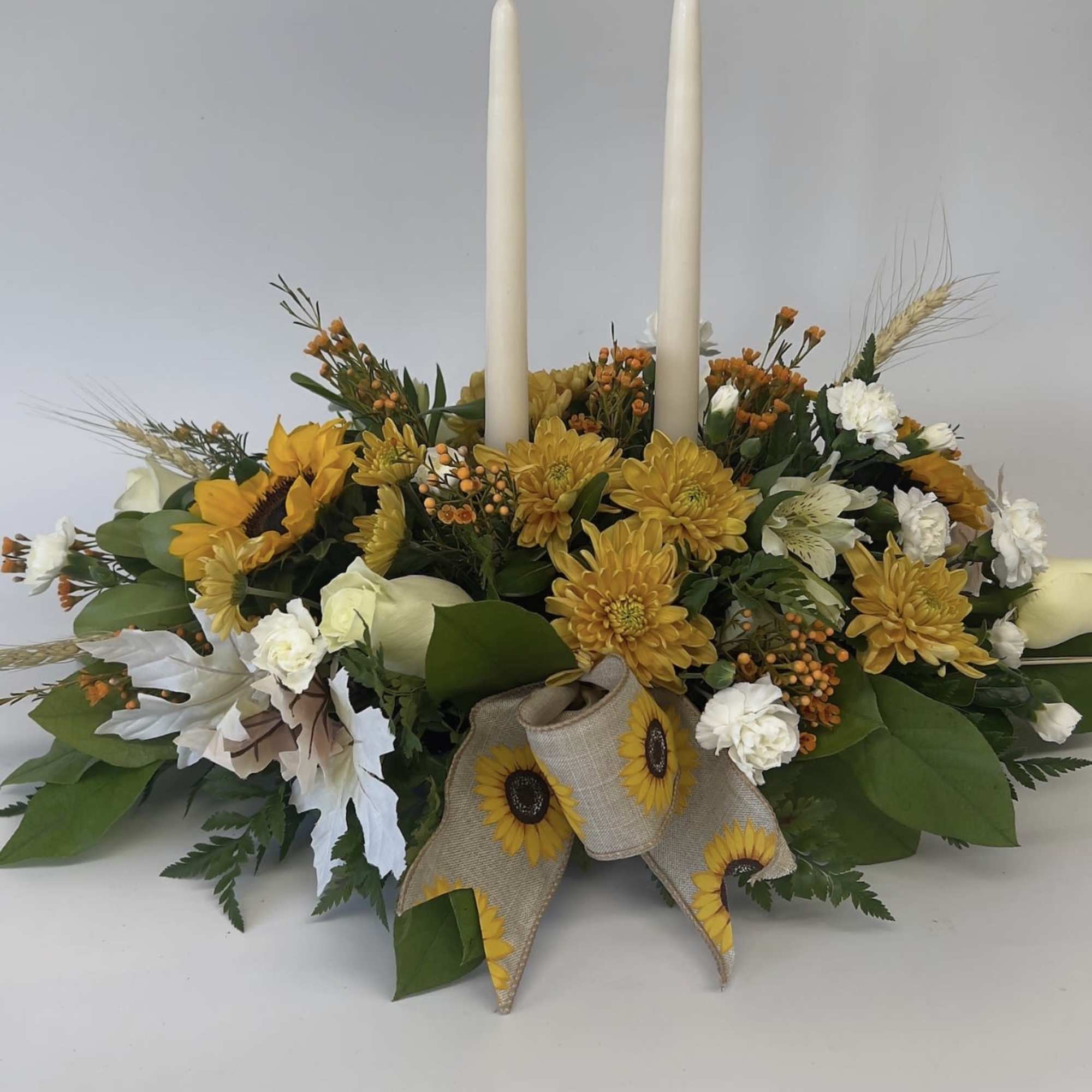 Yellow floral centerpiece with two white taper candles