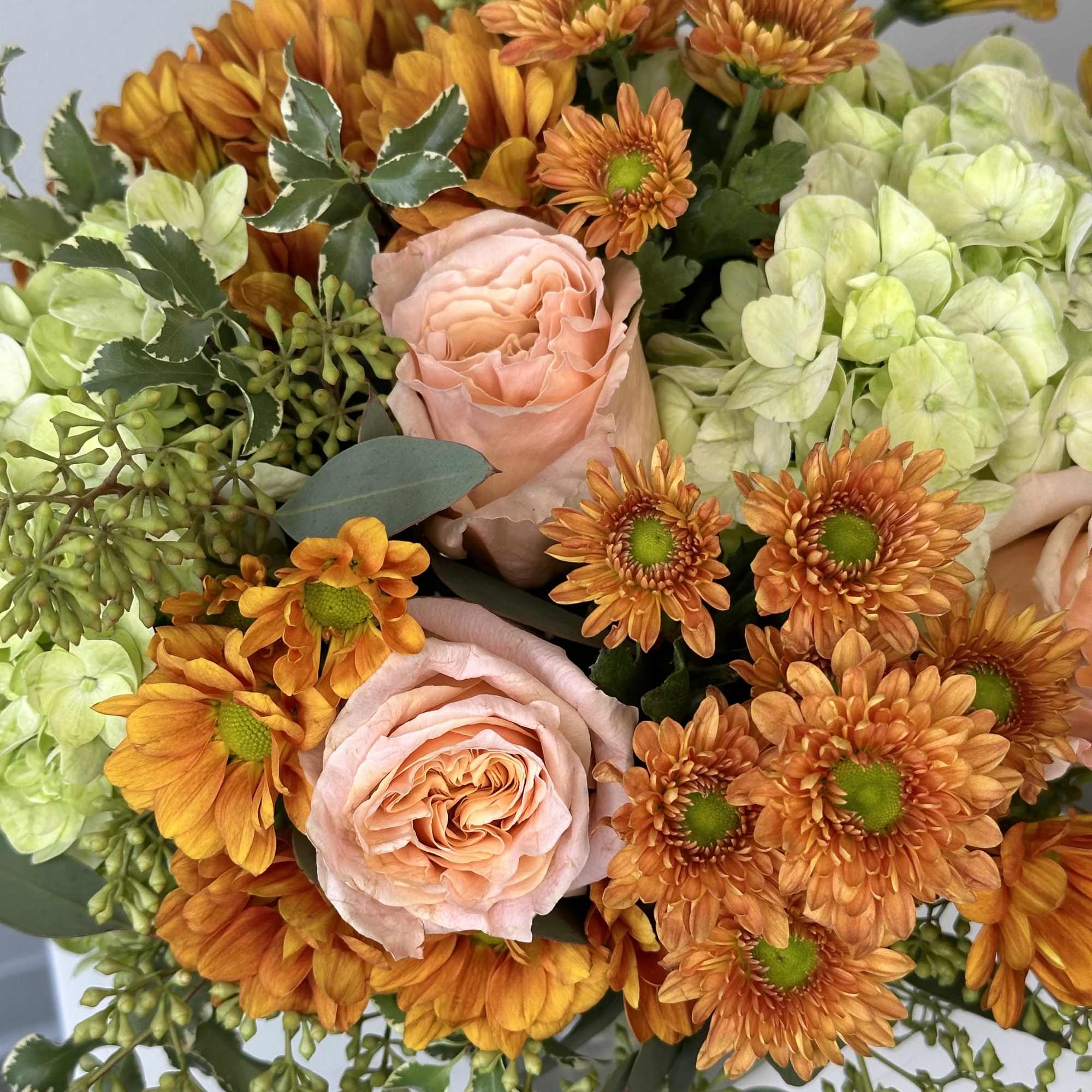 Bouquet of peach roses, orange chrysanthemums, and pale green hydrangeas