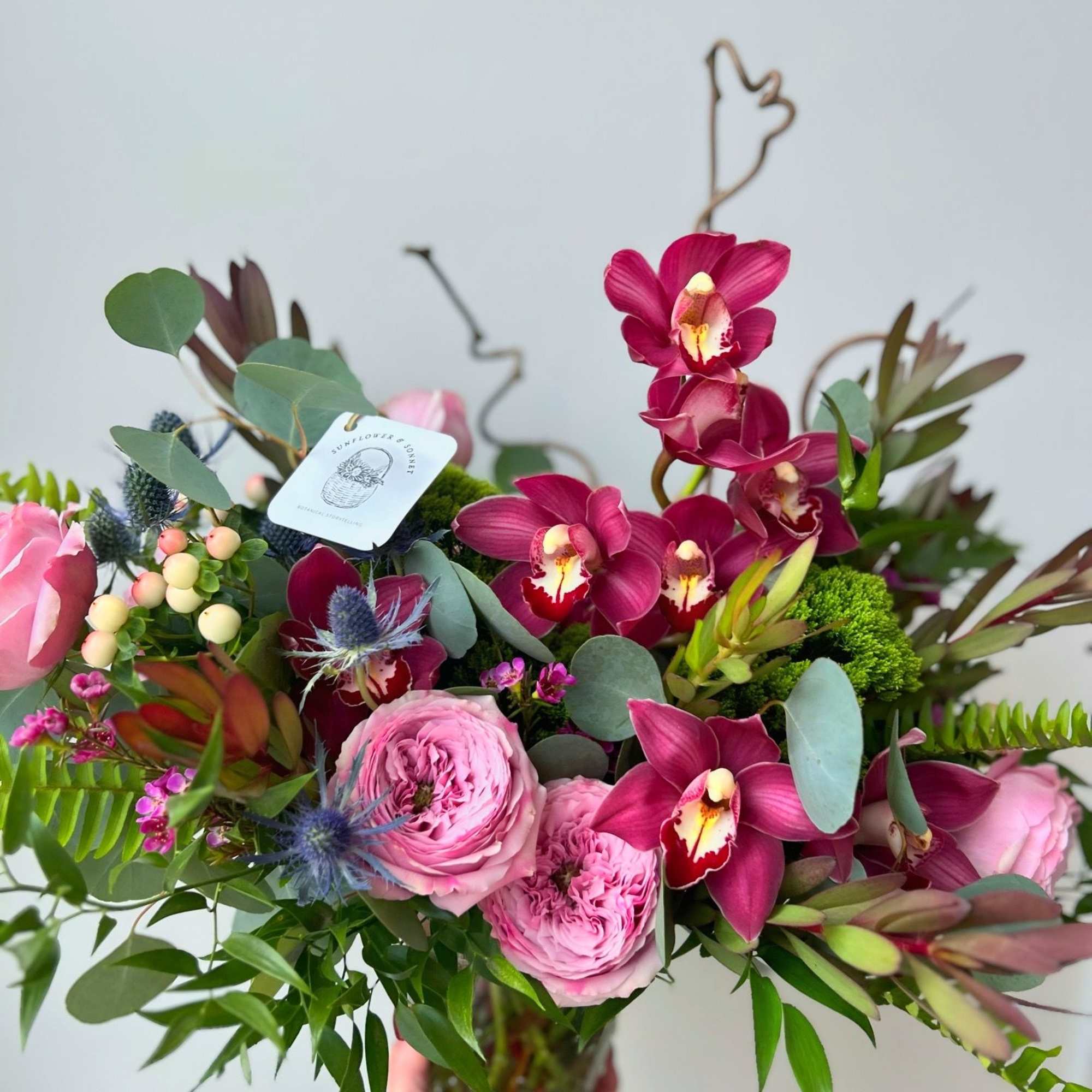 A lush composition of deep wine orchids and garden roses in blushing, photo 2 of 2