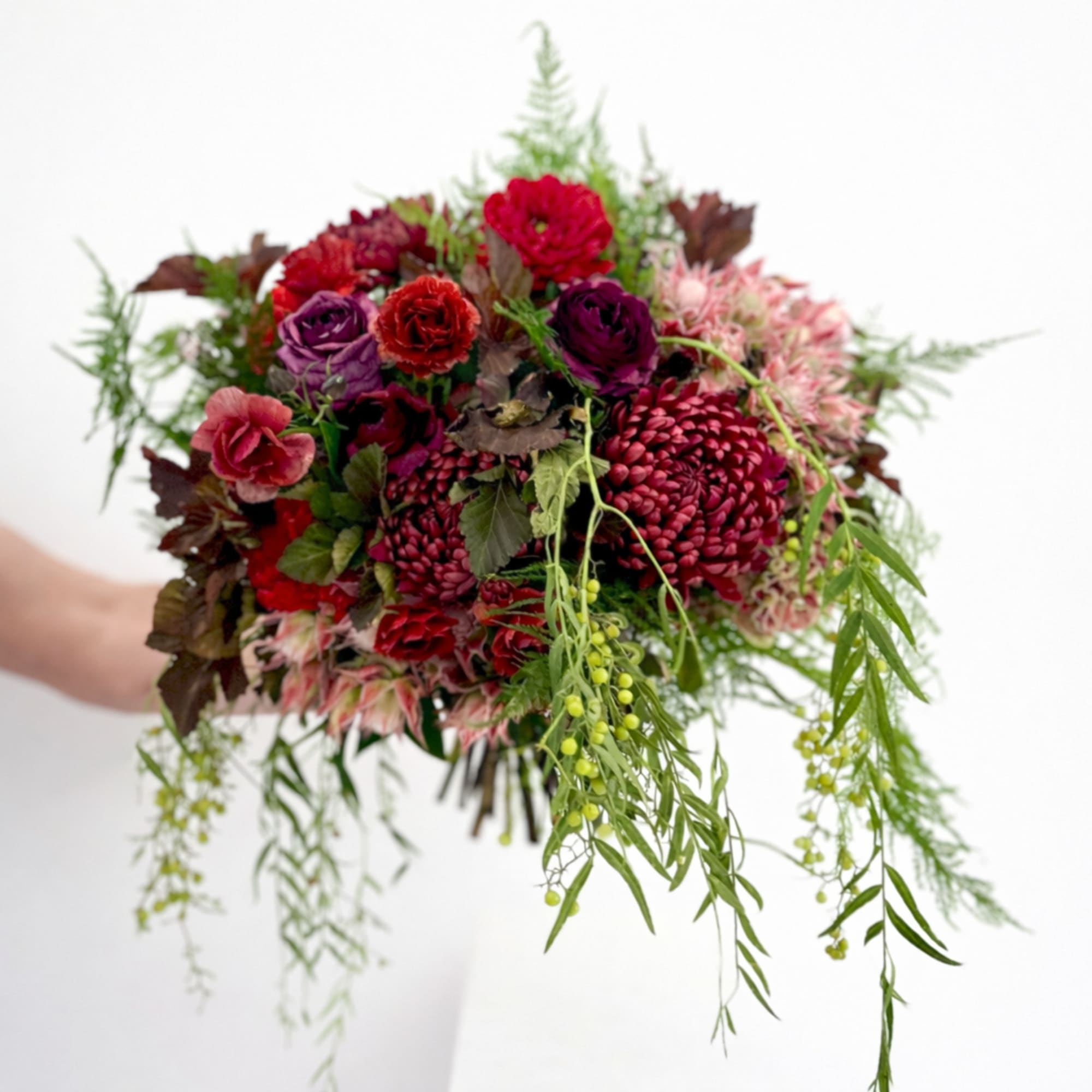 This bouquet is a dramatic and romantic gathering of jewel-toned blooms with
