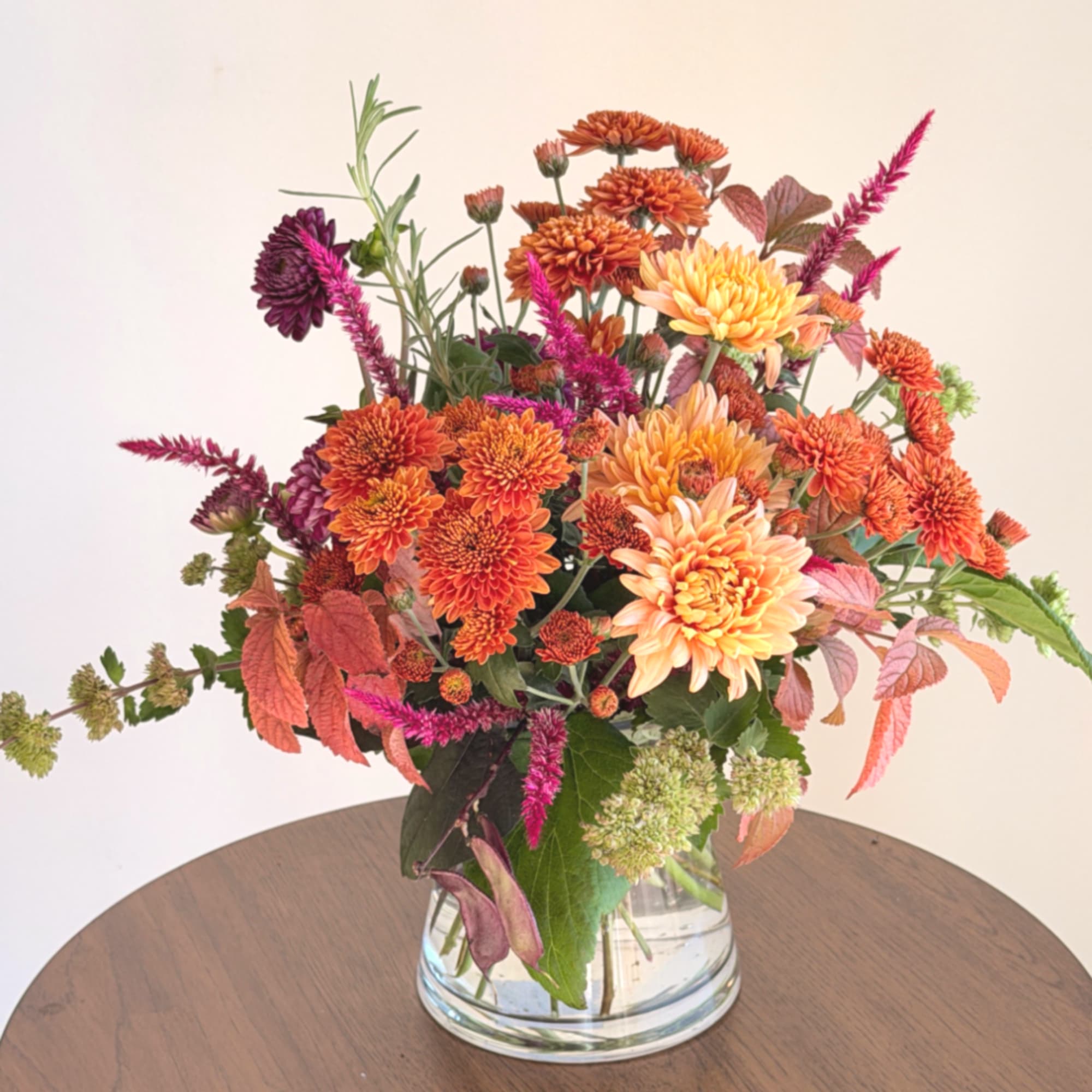 Orange and pink chrysanthemum bouquet in a clear glass vase
