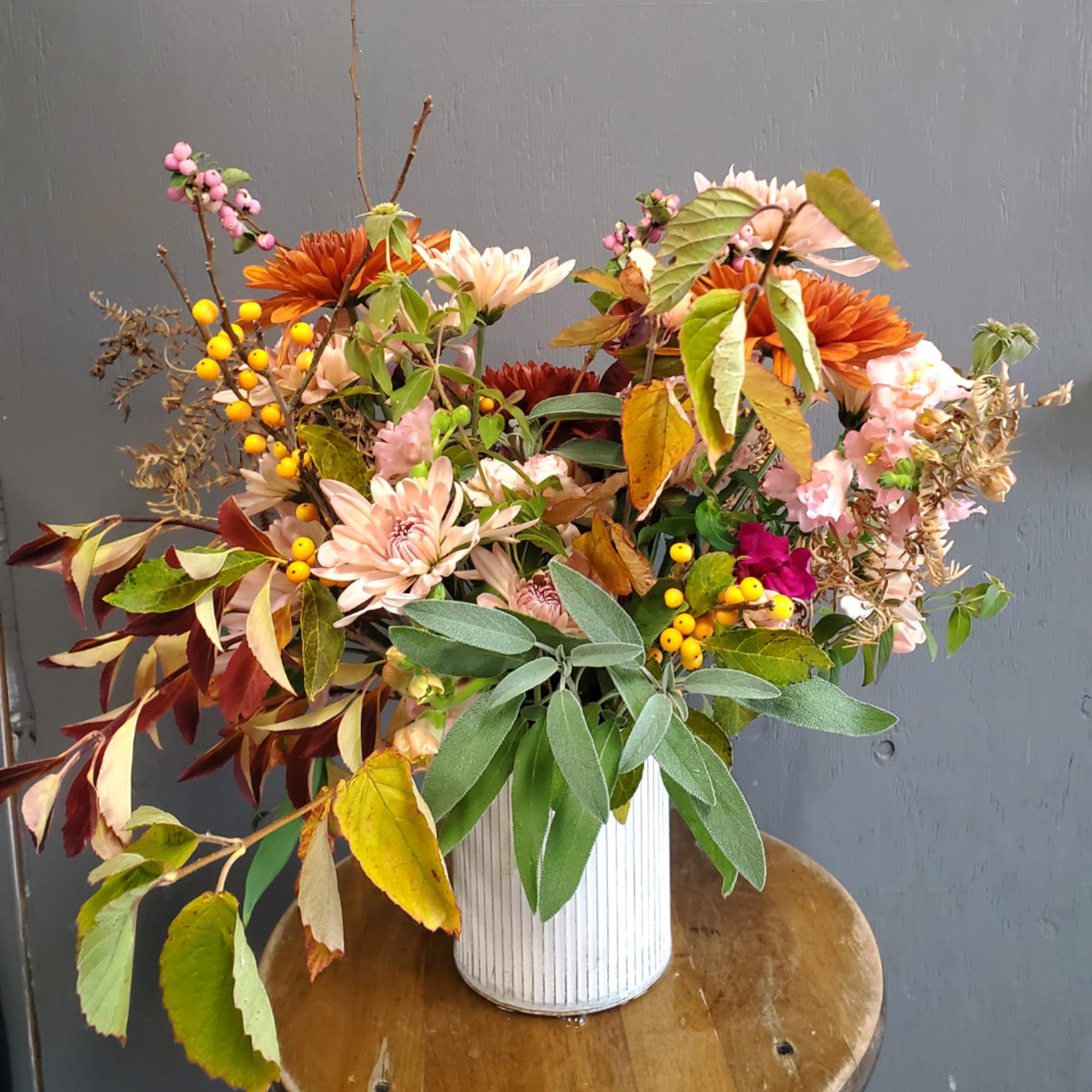 Mixed autumn bouquet in a white ribbed vase with orange and pink blooms